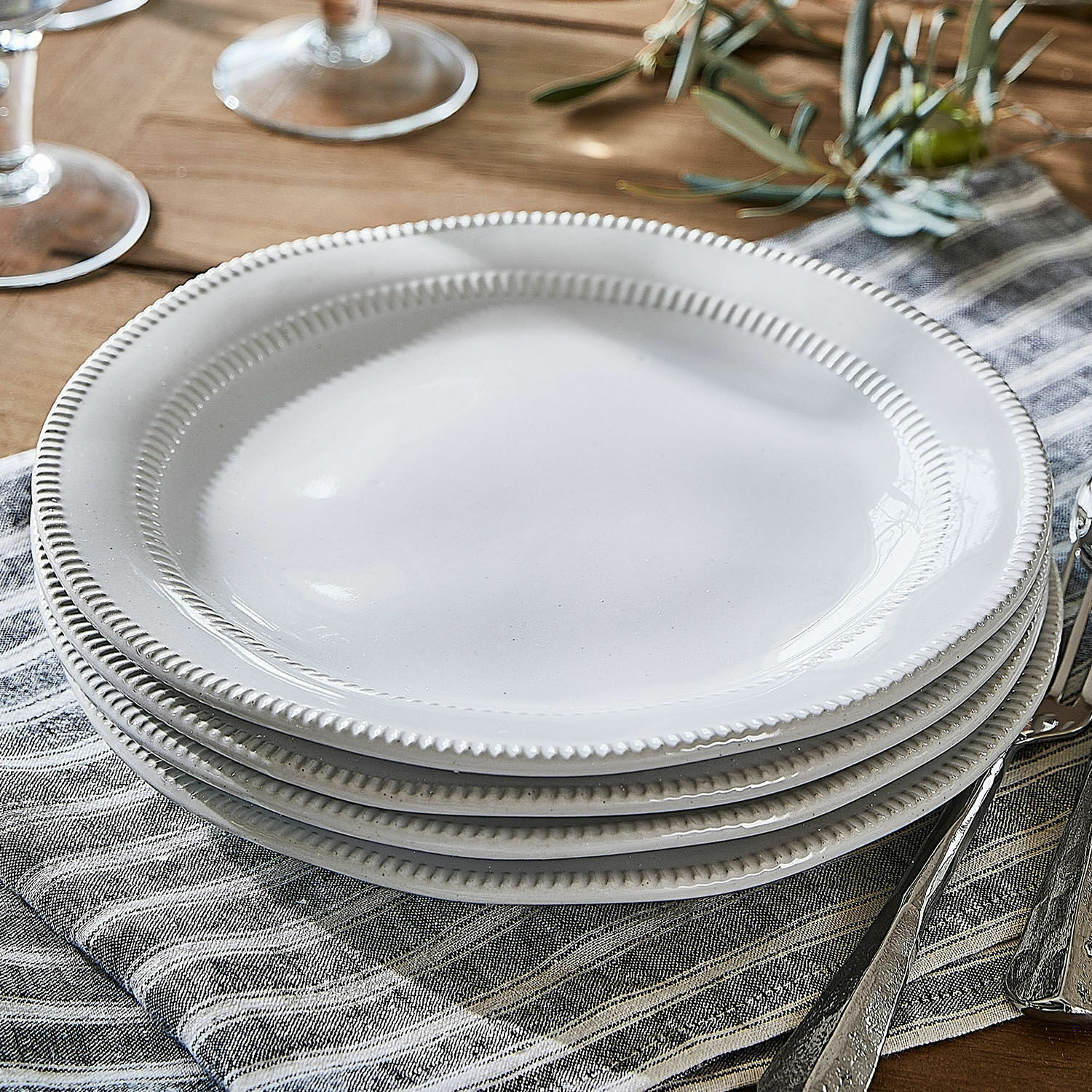 Kleine borden Alentejo Witte keramische borden met decoratieve rand op linnen servet op houten tafel gestapeld