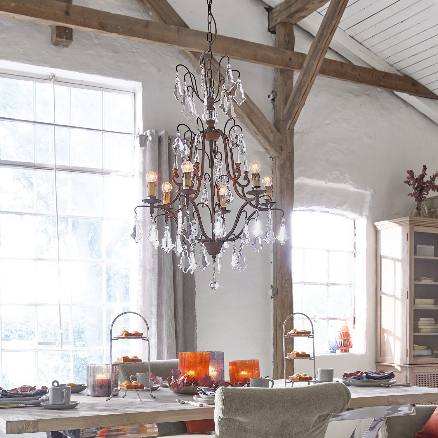 Kroonluchter Saint Pierre Rustieke metalen en kristallen kroonluchter boven houten tafel met decoraties in eetkamer