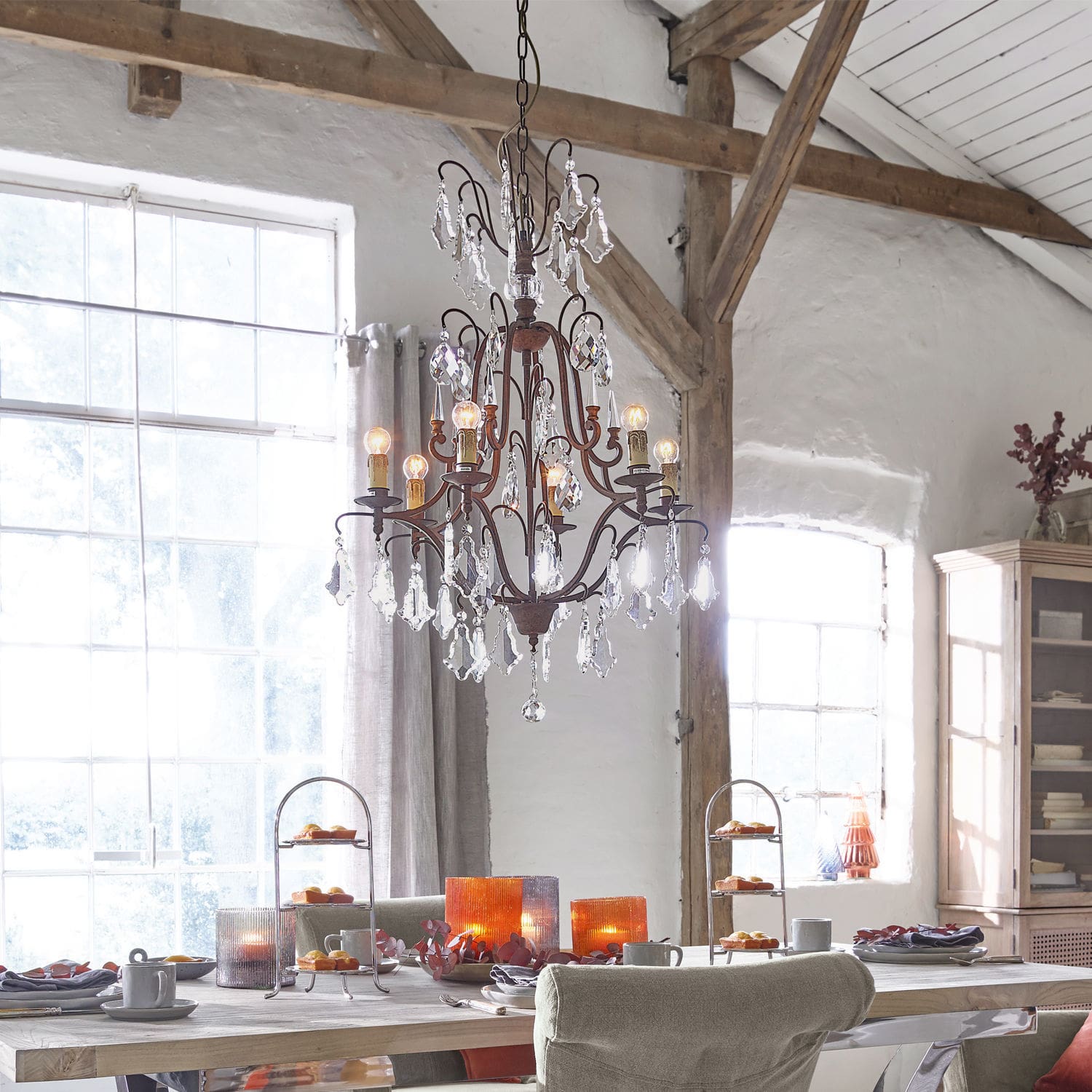 Kroonluchter Saint Pierre Rustieke metalen en kristallen kroonluchter boven houten tafel met decoraties in eetkamer