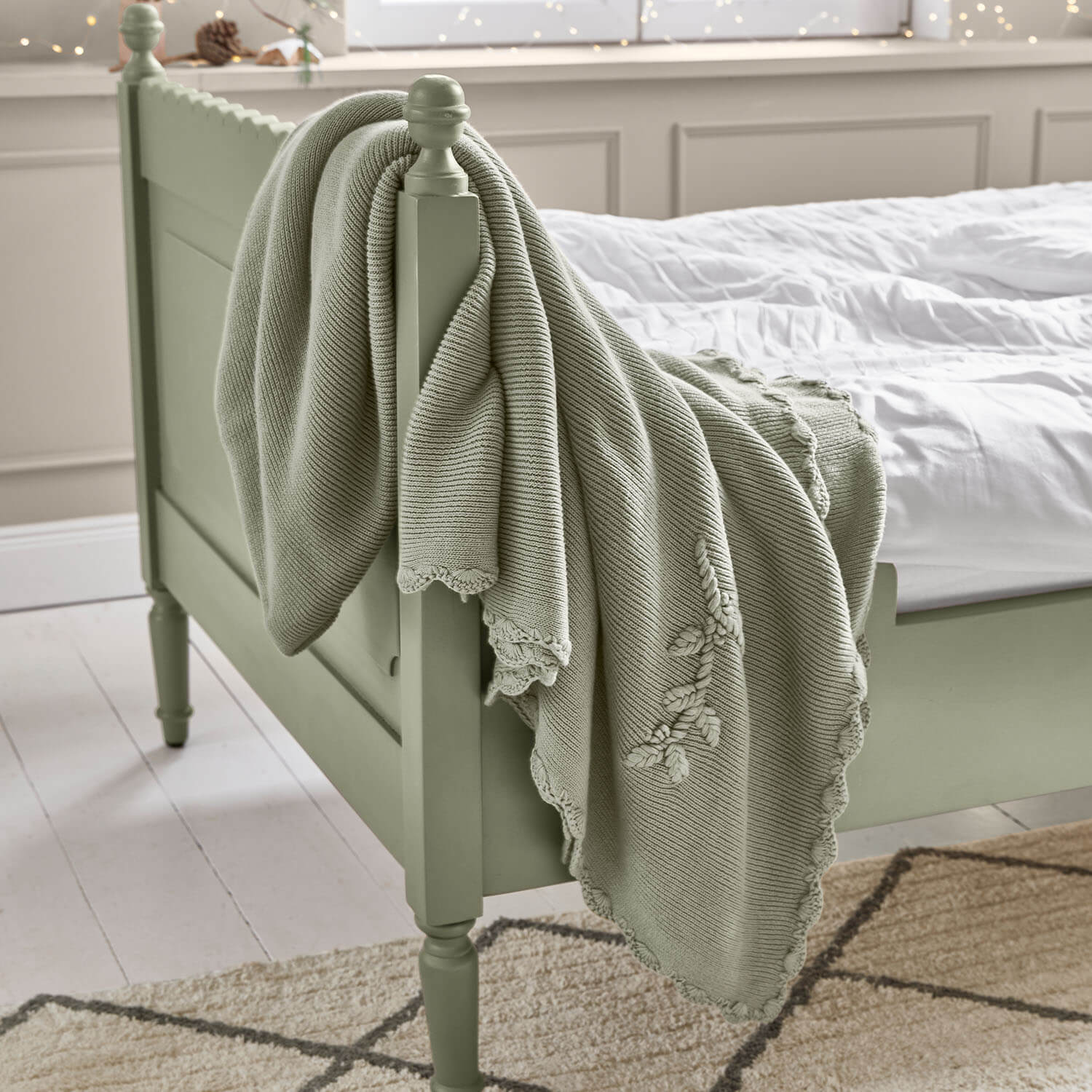 Plaid vert menthe en coton avec broderie décorative sur un lit en bois dans une chambre