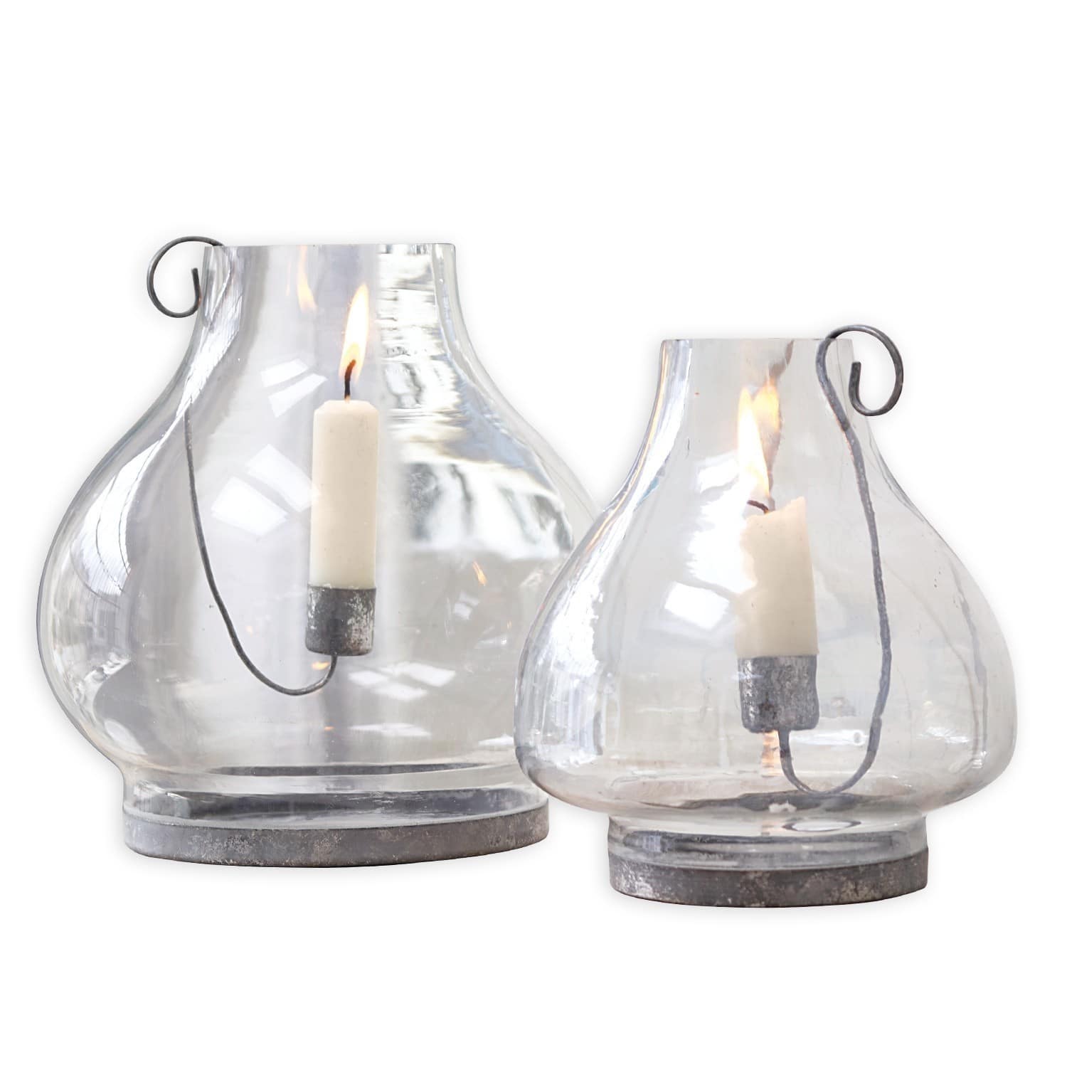 Ensemble de deux lanternes en verre transparent avec base en métal et bougies blanches allumées