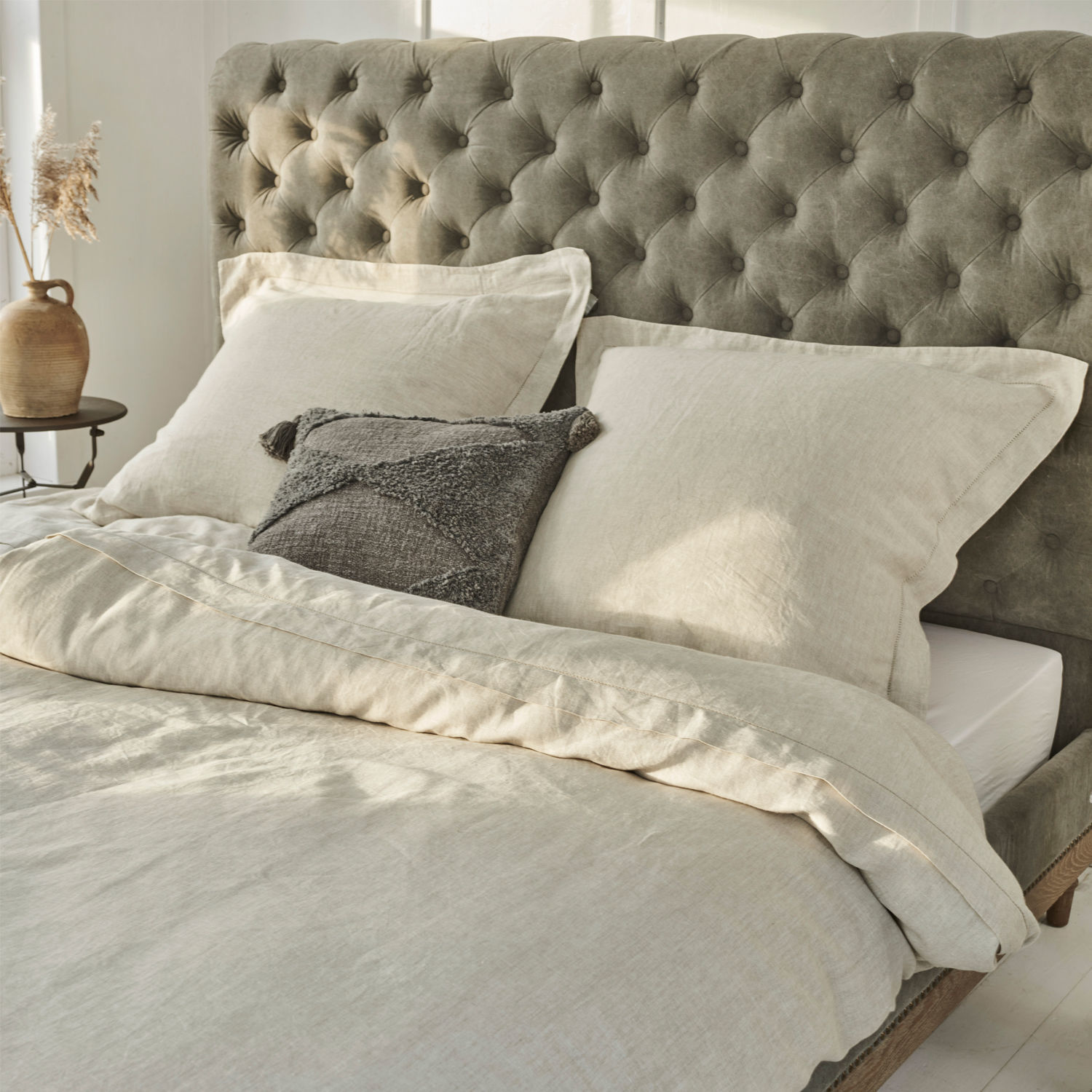 Parure de lit Kilanema Parure de lit beige en lin sur lit avec tête de lit capitonnée grise, coussin décoratif gris