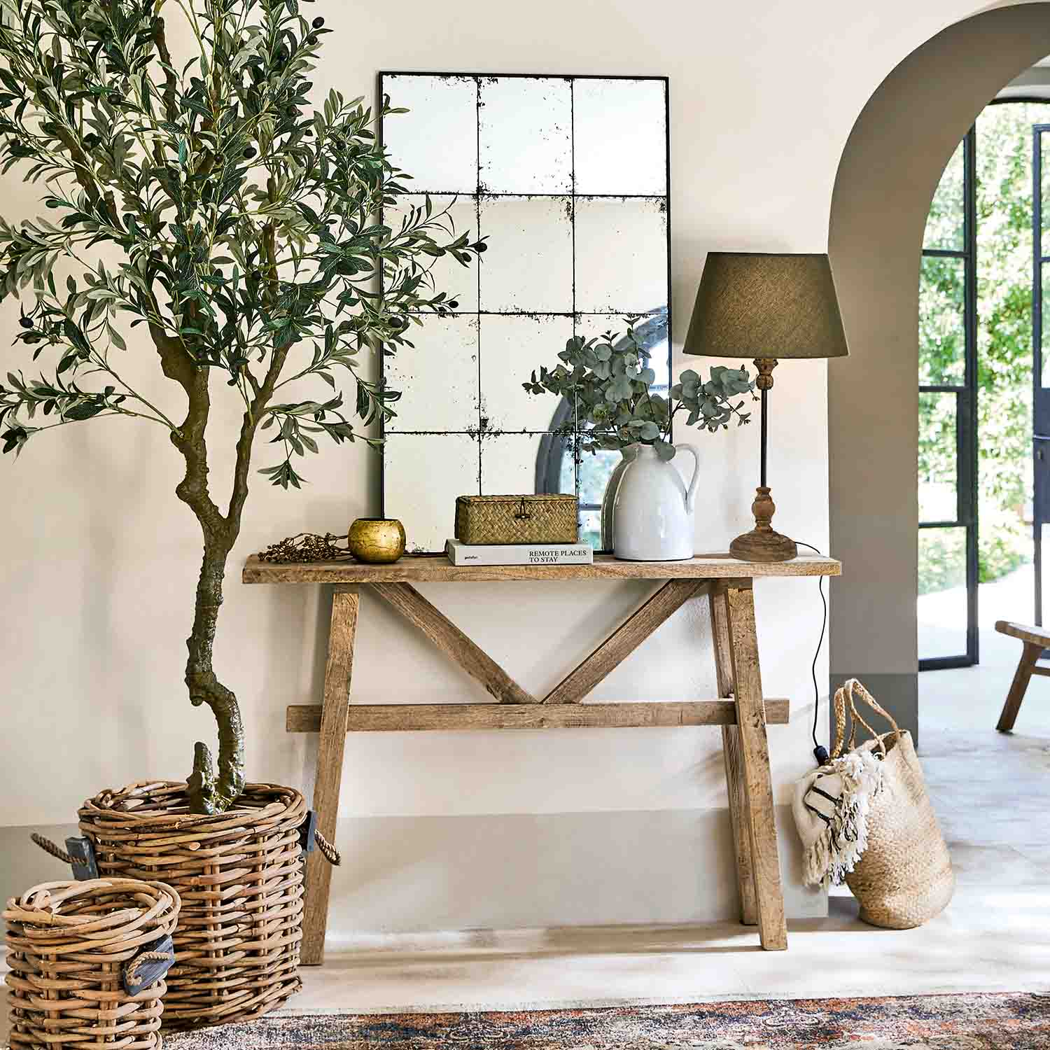 Houten sidetable met spiegel, lamp en rieten decoraties in lichte, natuurlijke kamer