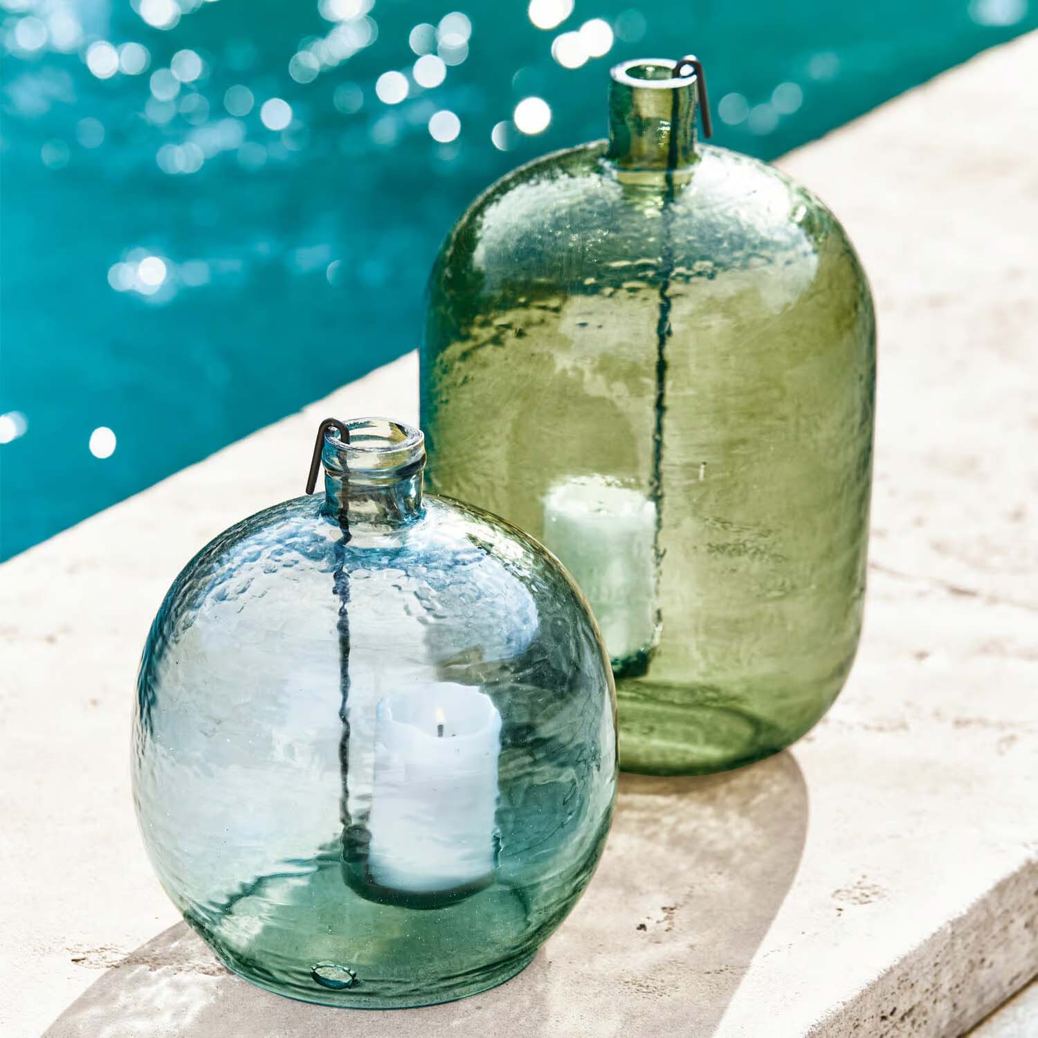 Lanterne en verre vert et bleu avec bougies blanches, décoration extérieure près de la piscine