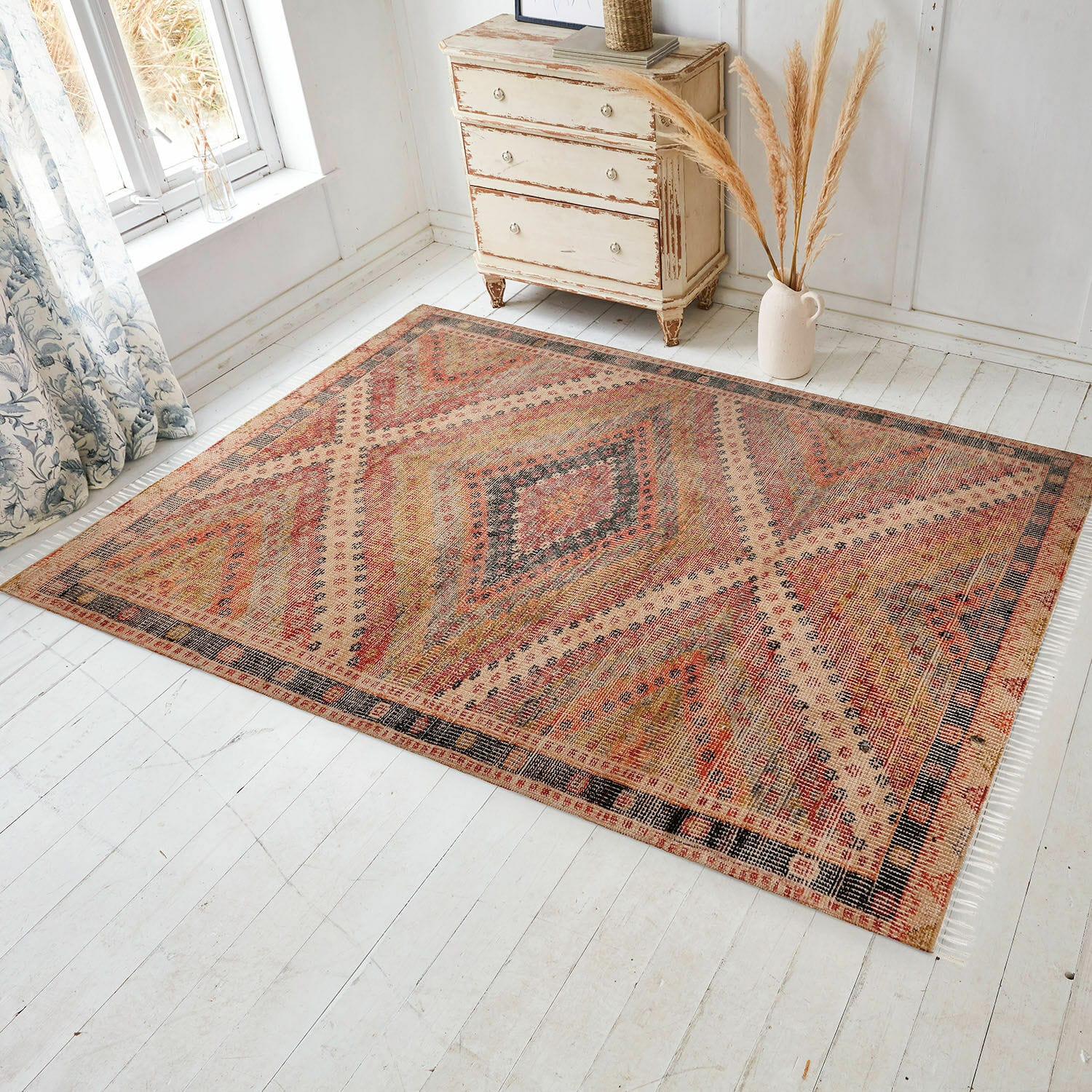 Vloerkleed voor binnen en buiten Mildura Vloerkleed met geometrisch patroon in warme rood- en beigetinten op lichte vloer in lichte kamer
