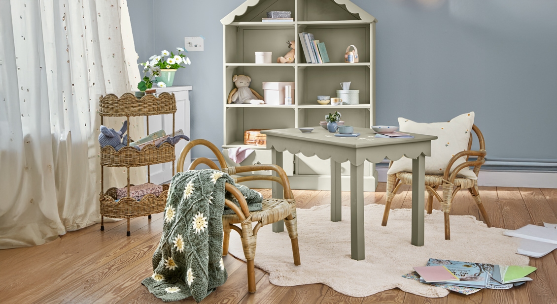 Chambre d'enfant bleu pastel avec table en bois et chaises en osier sur tapis clair