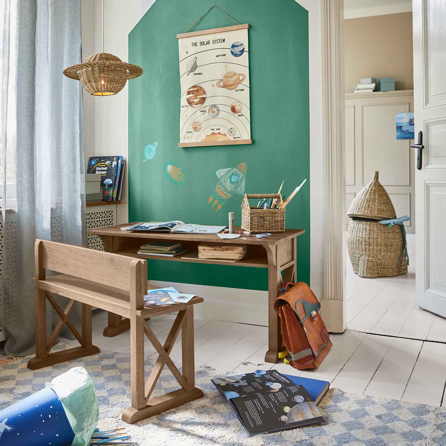 Houten bureau en bankje in kinderkamer met groene muur en poster van het zonnestelsel