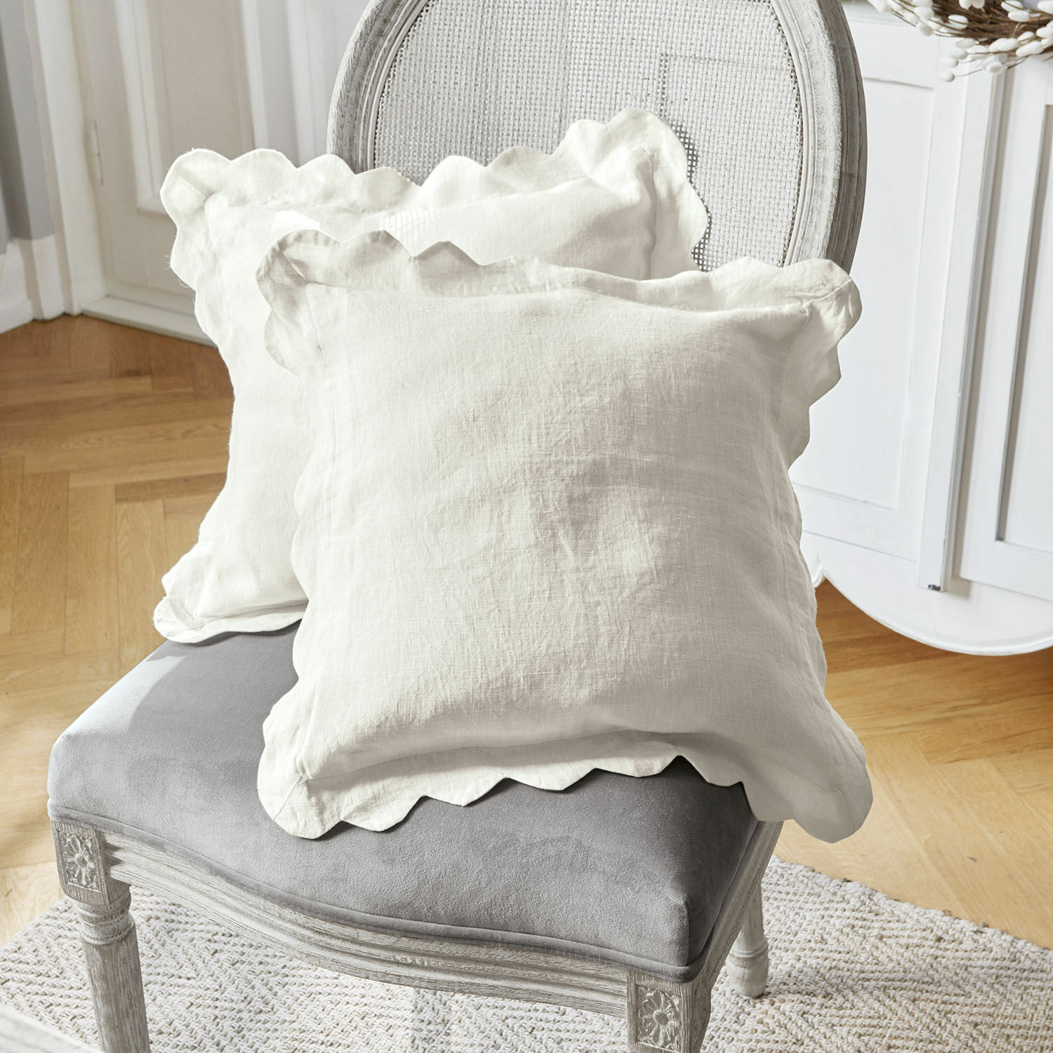Lot de 2 housses de coussins Fontienne Coussins décoratifs en lin blanc avec bord ondulé sur chaise grise rembourrée dans un salon