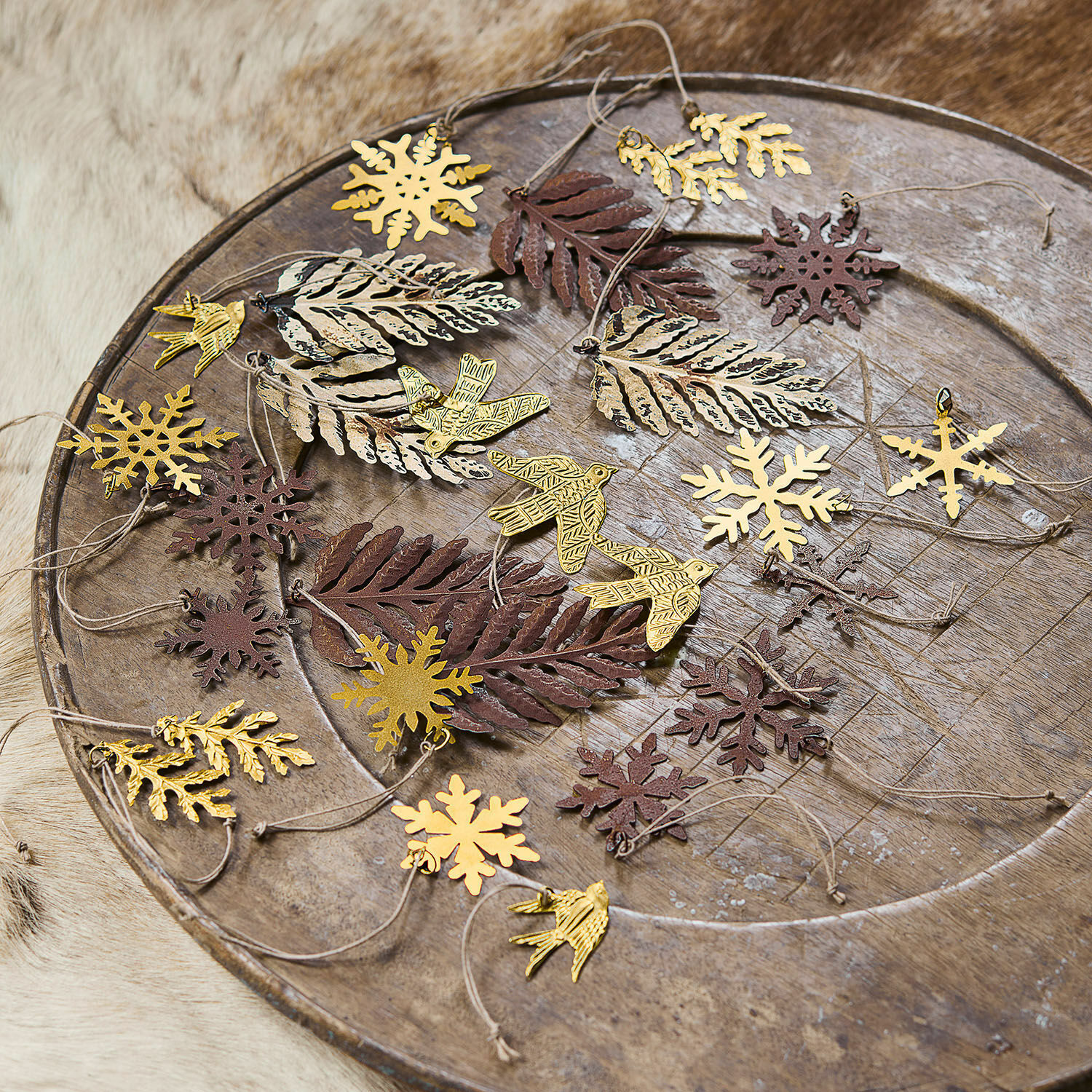 Kerstversiering set van 30 Mirabel Metalen decoraties in de vorm van bladeren, vogels en sneeuwvlokken in goud en bruin op een houten schaal