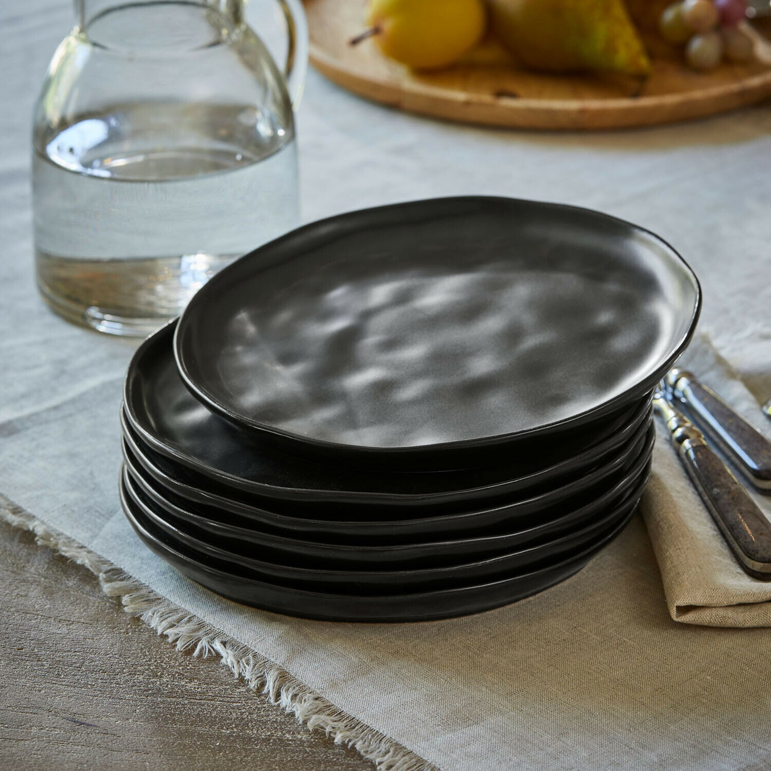 Lot de 6 assiettes à dessert Biarré Assiettes en céramique noire empilées sur un plateau en bois avec muffin et serviette blanche