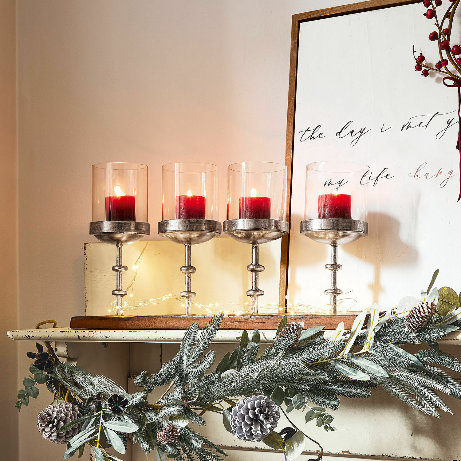 Ensemble de quatre bougeoirs en verre et métal avec bougies rouges, décoration de Noël avec pommes de pin