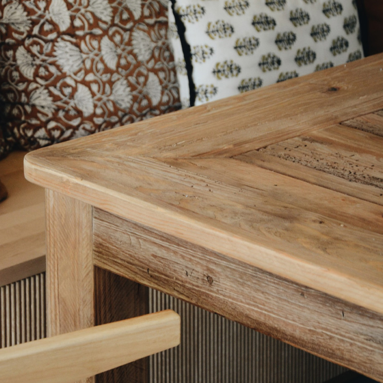 Table en bois clair au style rustique avec coussins décoratifs en arrière-plan, mobilier de salon