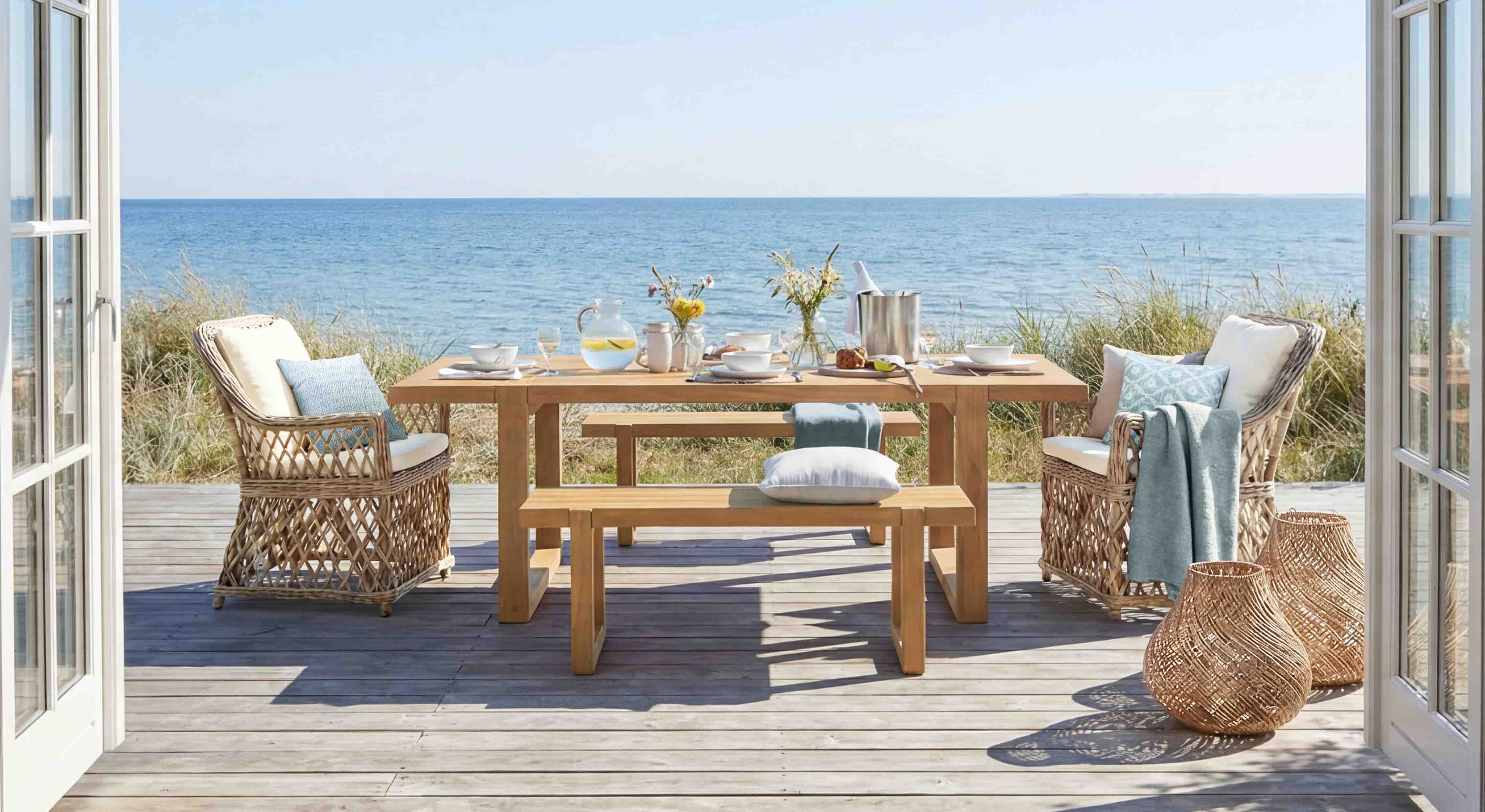 Ensemble de mobilier de jardin en bois et rotin naturel sur terrasse avec vue sur la mer