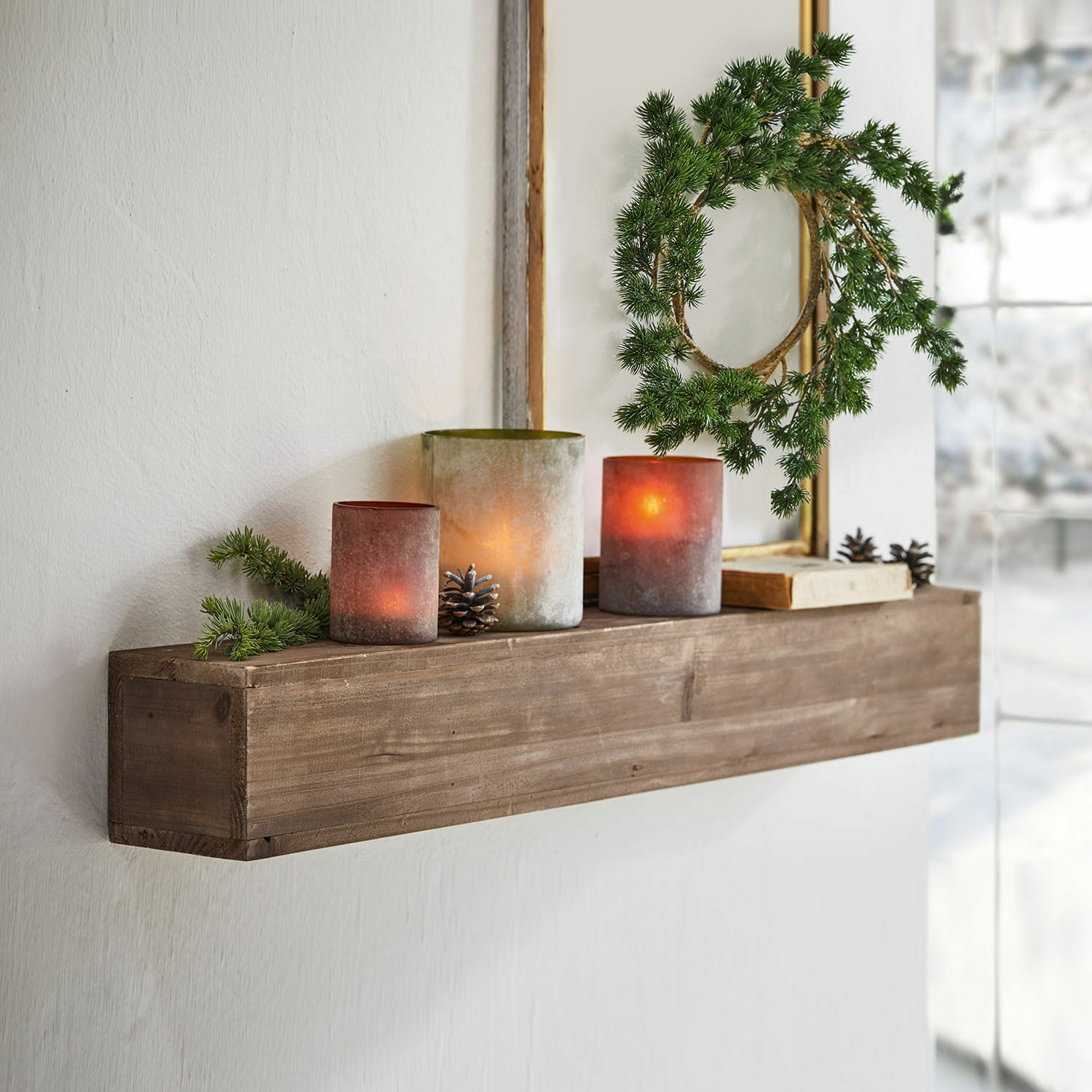 Wandplank Visayas Houten wandplank met decoratieve kaarsen en groene krans in lichte kamer