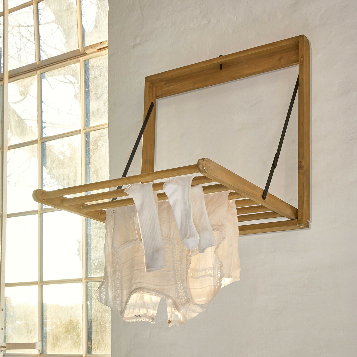 Étendoir à linge mural Élirème Séchoir mural pliant en bois clair avec vêtements blancs suspendus dans une pièce lumineuse
