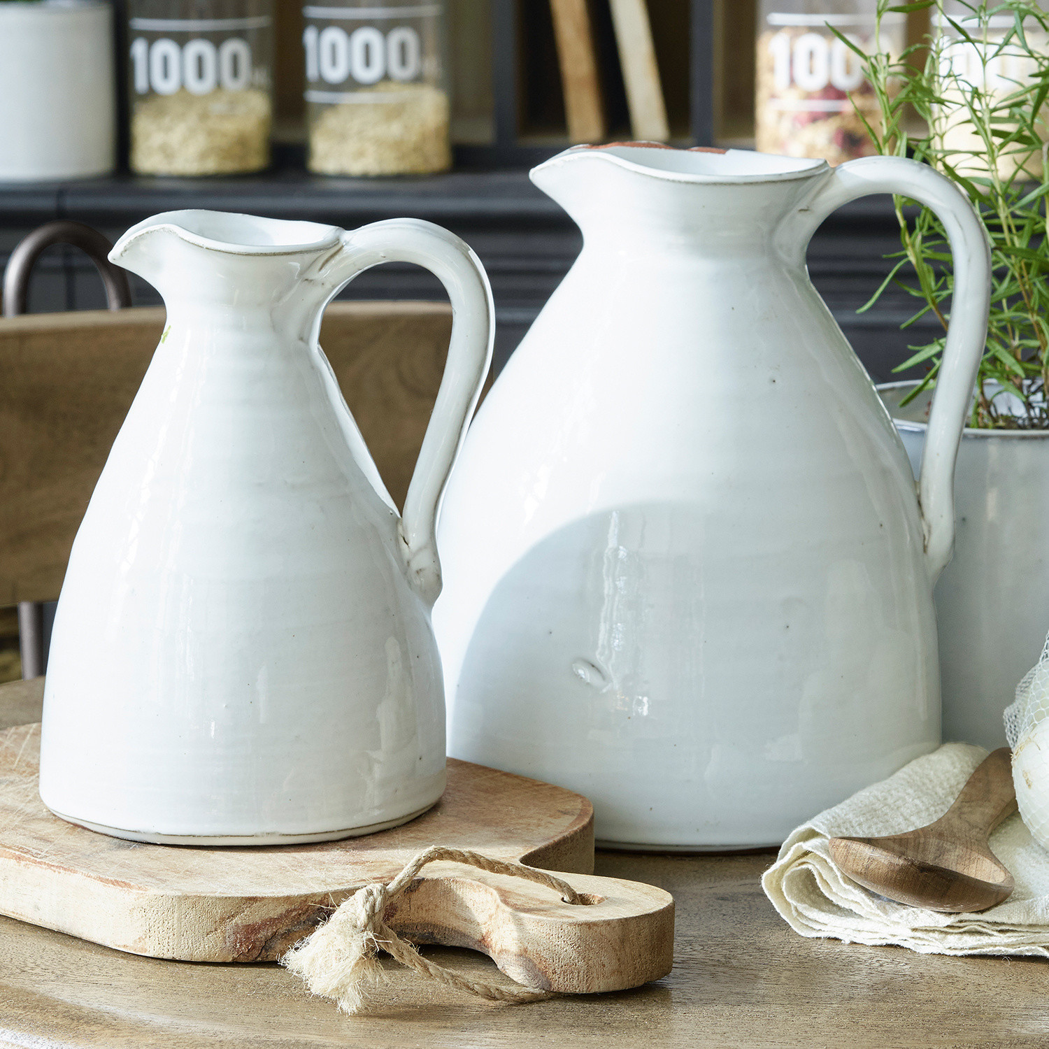 Vaas set van 2 Yarick Twee witte keramische kannen op een houten snijplank in een rustieke keuken
