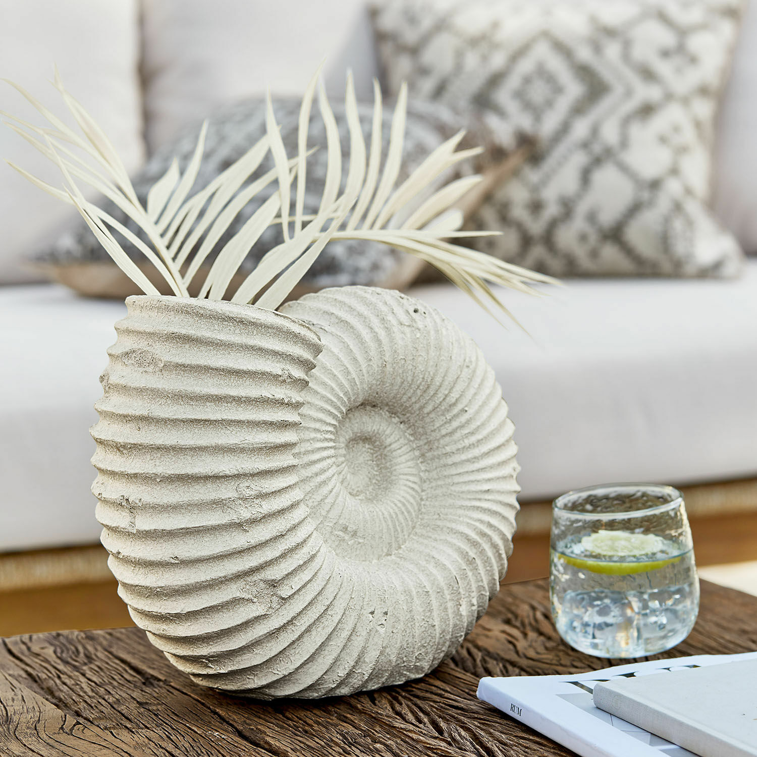 Vaas Korrellin Decoratieve betonnen schelpvaas met lichte bladeren op houten tafel in woonkamer