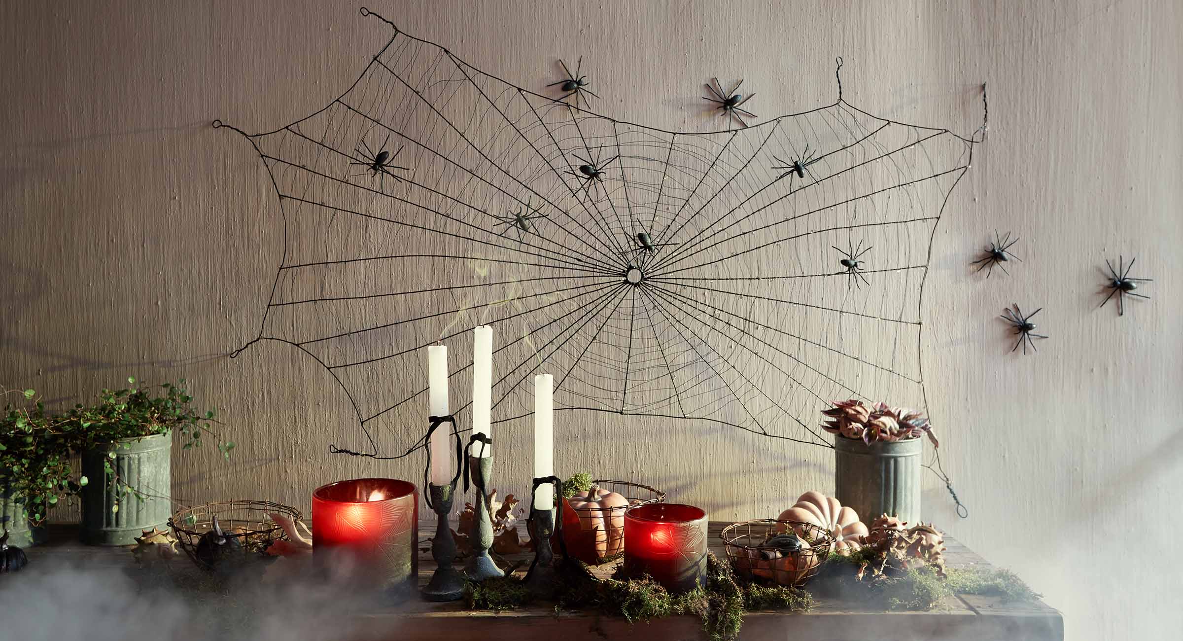 Décoration Halloween avec toile d'araignée noire et araignées sur le mur, bougies et citrouilles sur la table