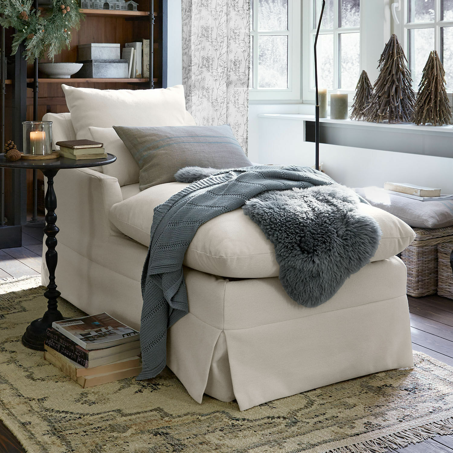 Fauteuil rembourré beige avec coussins doux et plaid gris dans un salon chaleureux