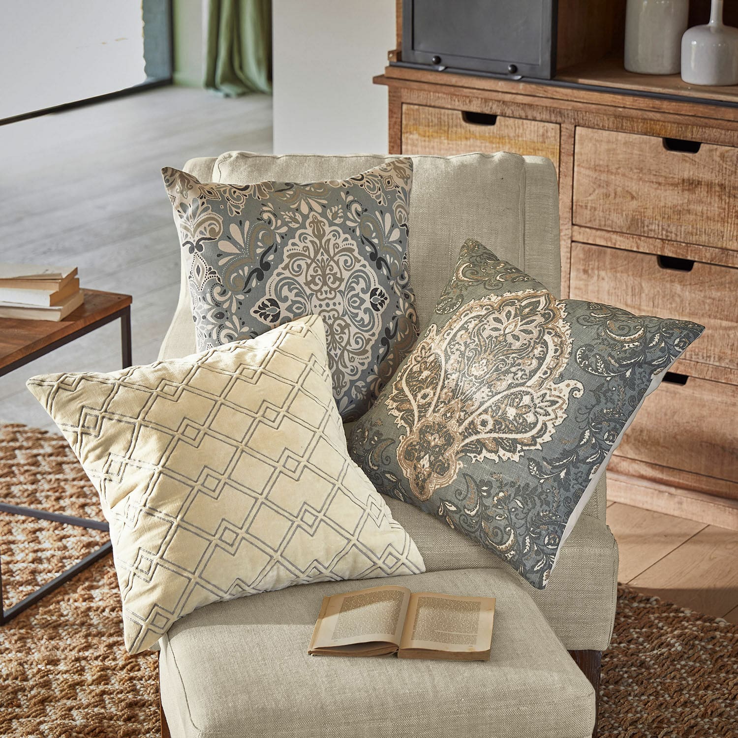 Kussenhoes set van 3 Madalena Drie decoratieve kussens met beige en grijze patronen op een lichte fauteuil in de woonkamer