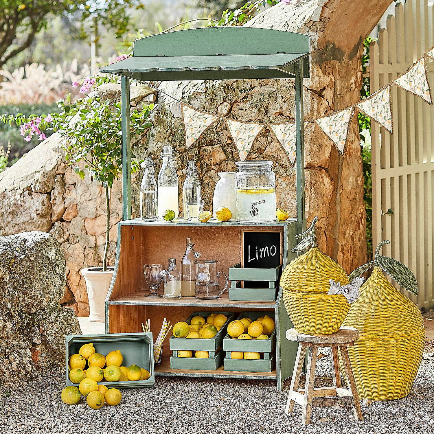 Limonadekraam Éclairon Groene houten stand met citroenen en glazen flessen voor limonade in de tuin