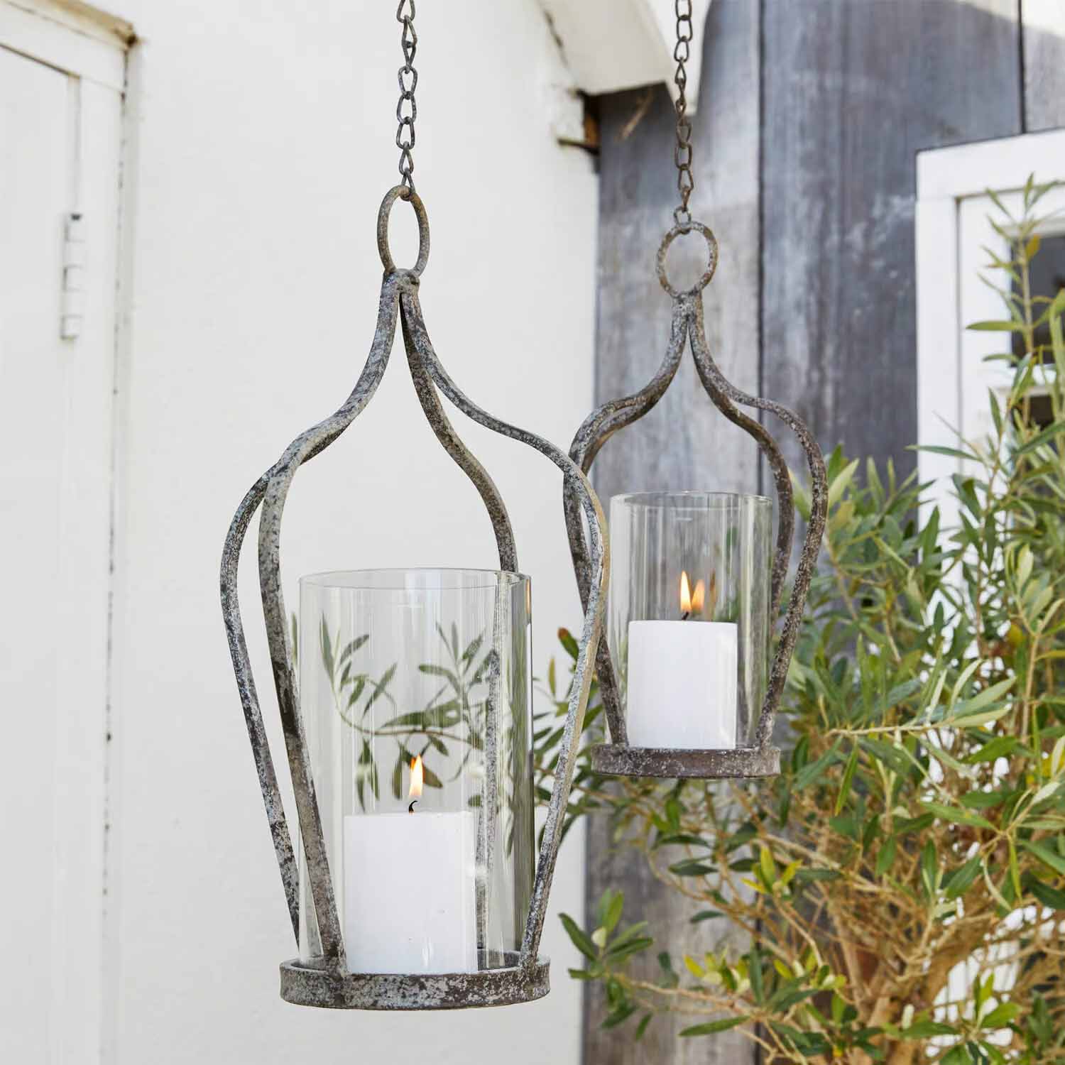 Hangende metalen lantaarns in vintage stijl met witte kaarsen en glazen bescherming voor tuindecoratie