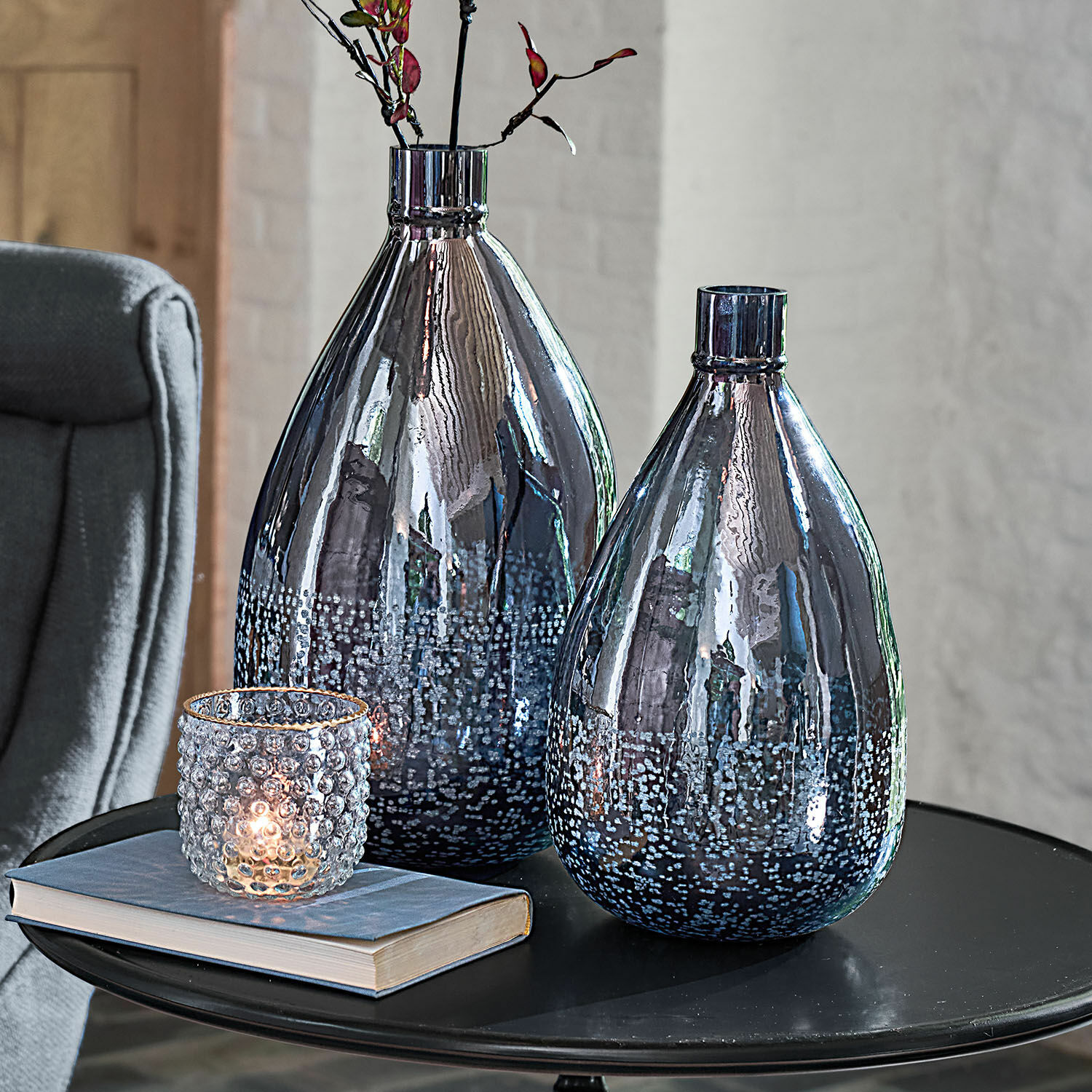 Vaas set van 2 Qilevon Twee decoratieve rookglas vazen met bubbels patroon op zwarte tafel met boek en windlicht