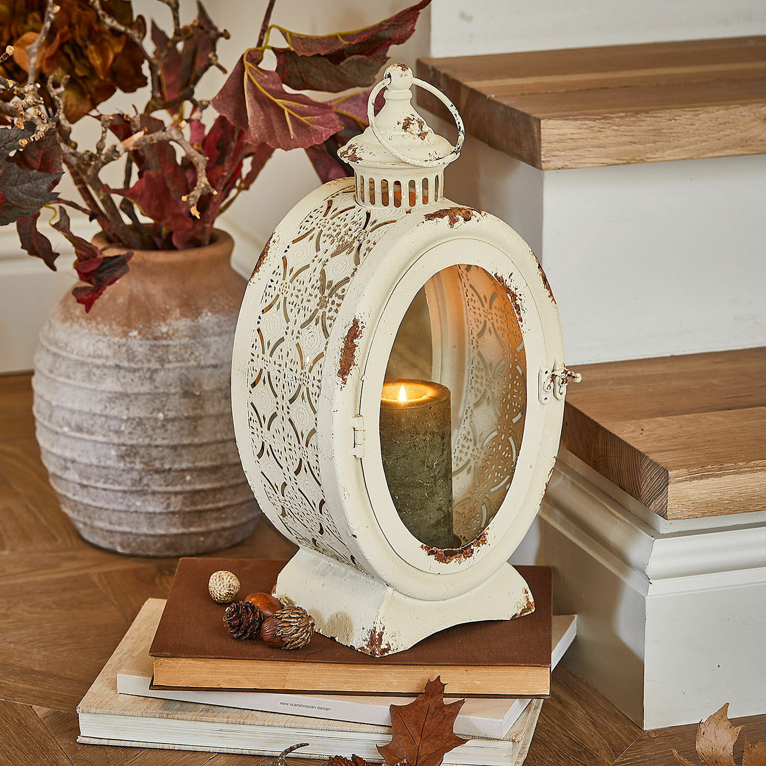 Lantaarn Sublimelle Vintage metalen lantaarn in crème met brandende kaars en herfstdecoratie op boeken