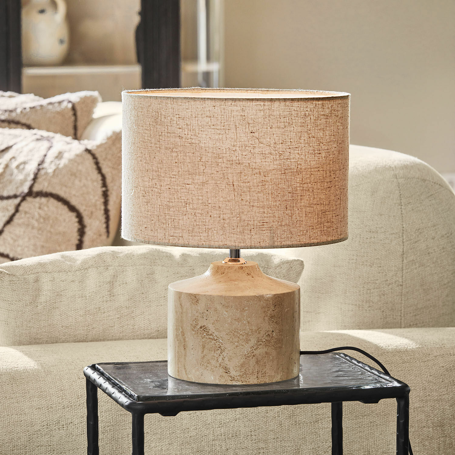 Lampe à poser Caleneuve Lampe de table avec abat-jour beige et base en marbre posée sur une table noire dans un salon