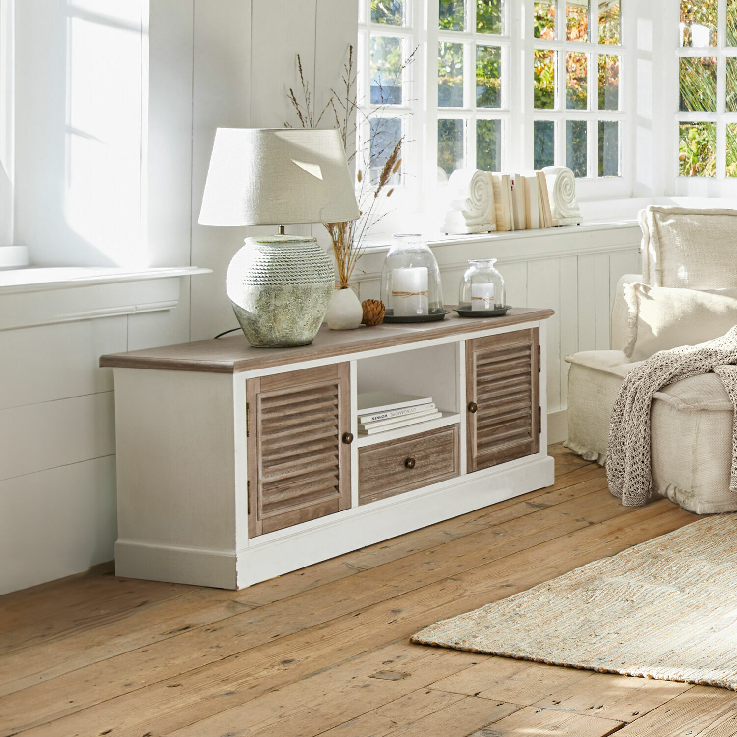 Meuble bas Glencoe Buffet en bois rustique blanc avec portes marron, lampe et décorations sur le dessus dans un salon lumineux