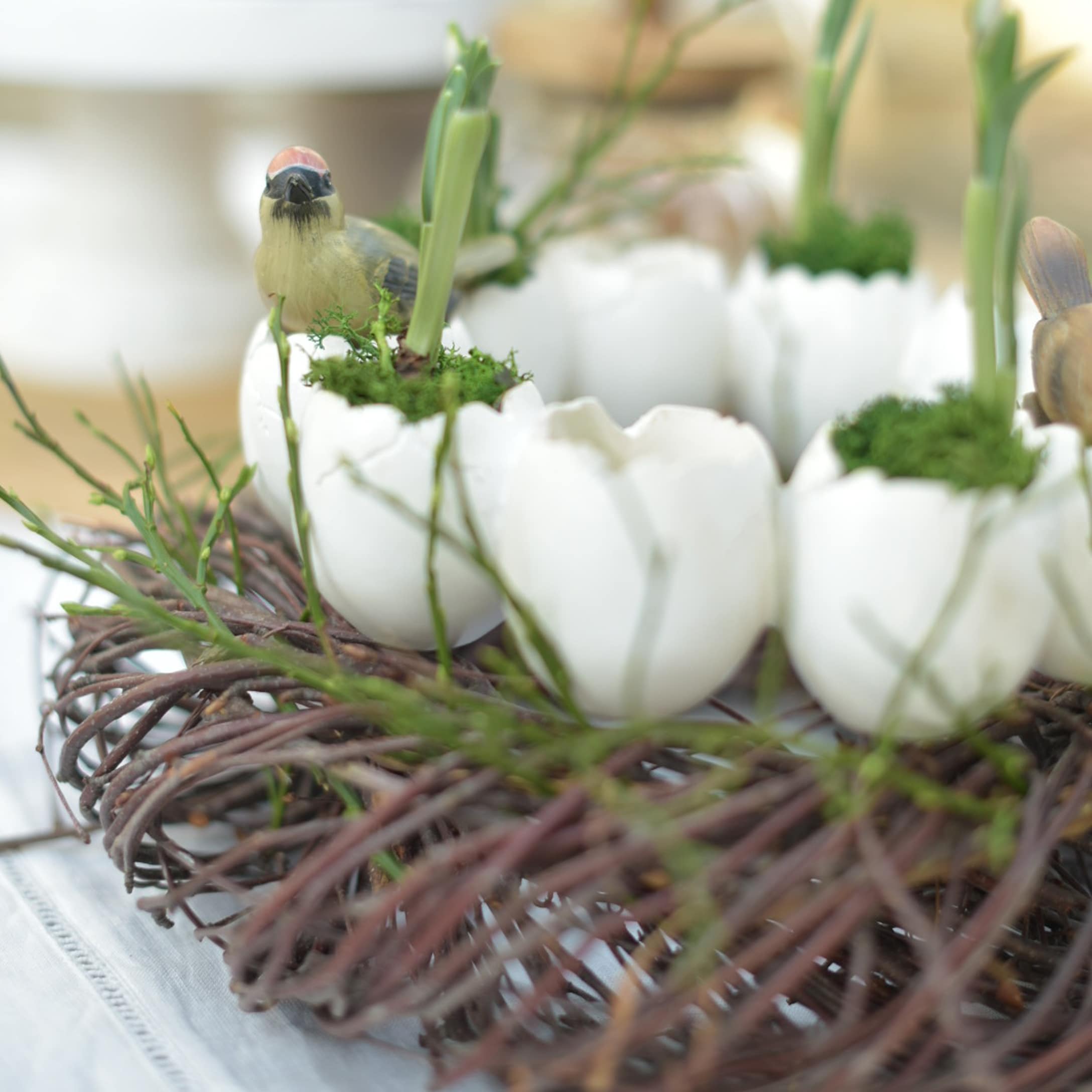 Couronne décorative avec œufs en céramique blanche, mousse verte et oiseaux artificiels pour Pâques