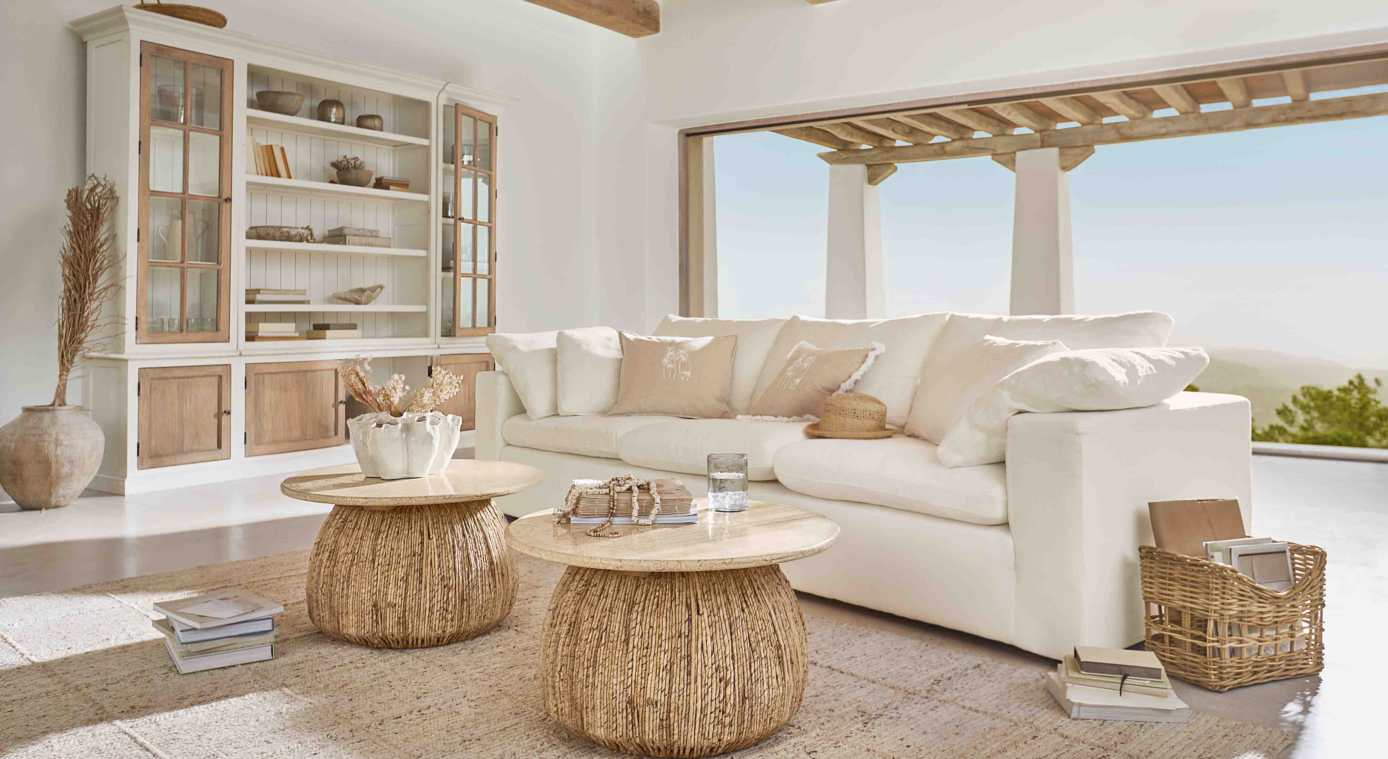 Salon lumineux avec canapé blanc et deux tables basses rondes en bois naturel et rotin