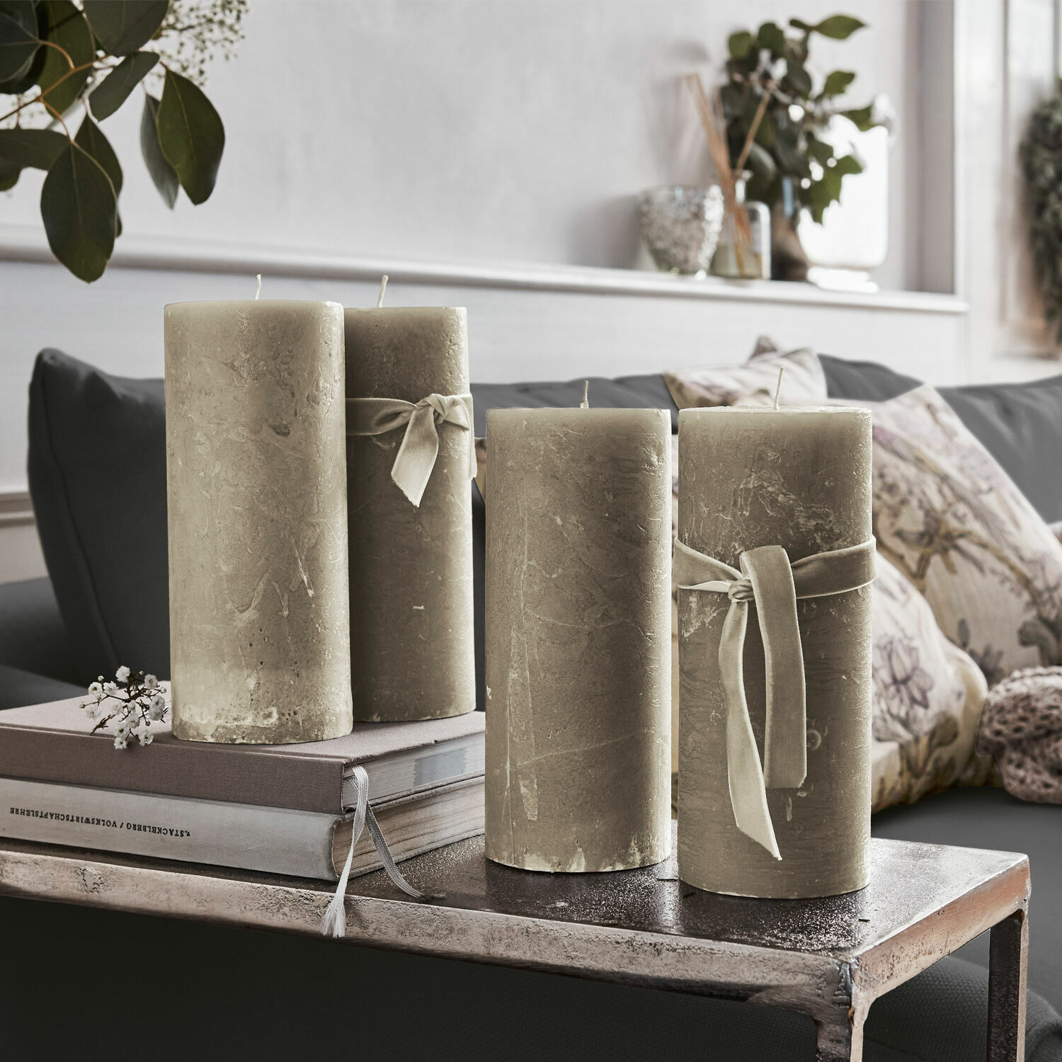 Set van vier beige decoratieve kaarsen met linten op metalen tafel in woonkamer