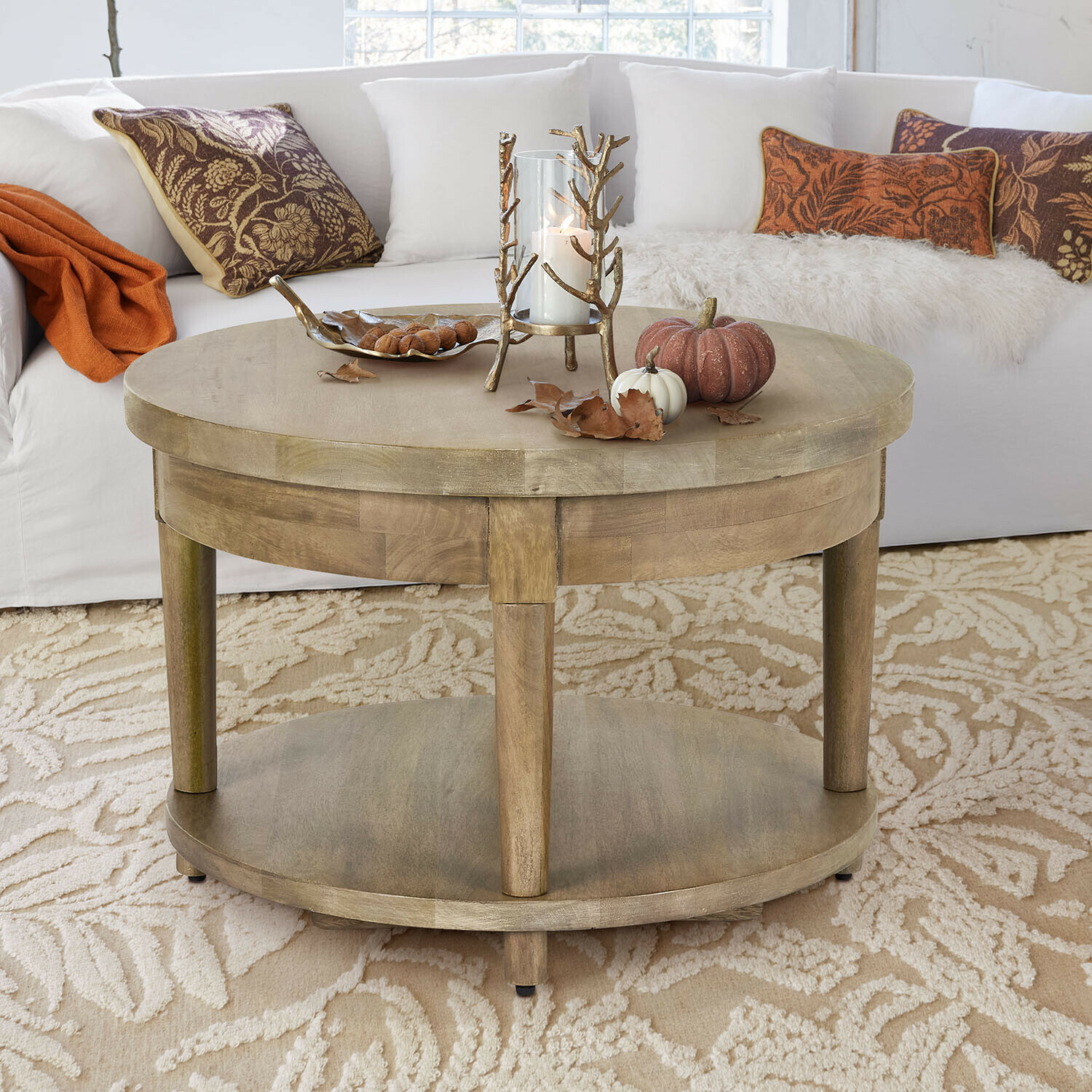 Salontafel Talinar Ronde houten salontafel in natuurlijke kleur met kaars- en pompoendecoratie op beige tapijt