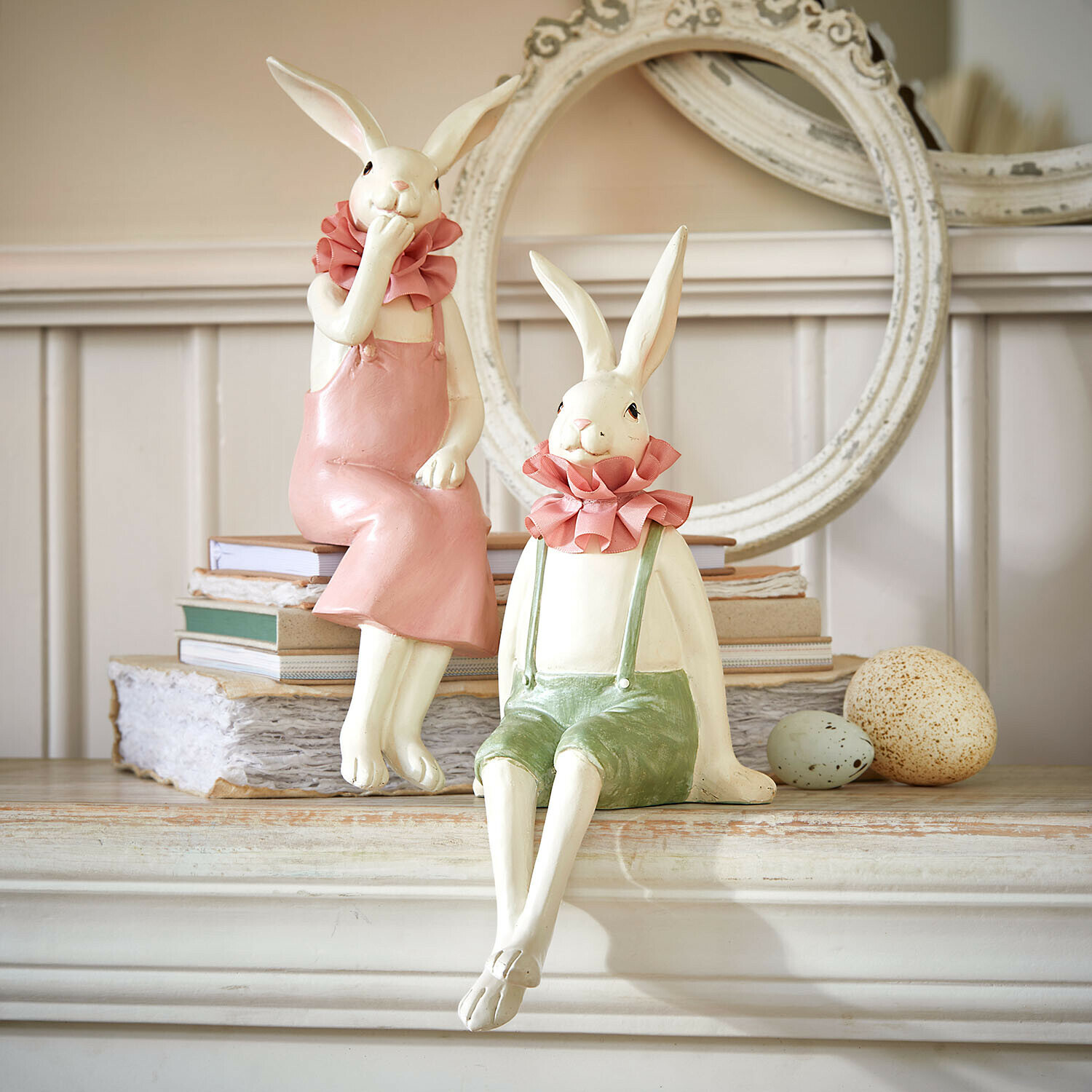 Lot de 2 lapins décoratifs Vent Élysien Figurines décoratives de lapins en céramique vêtus de tenues pastel posées sur une cheminée avec livres et œufs