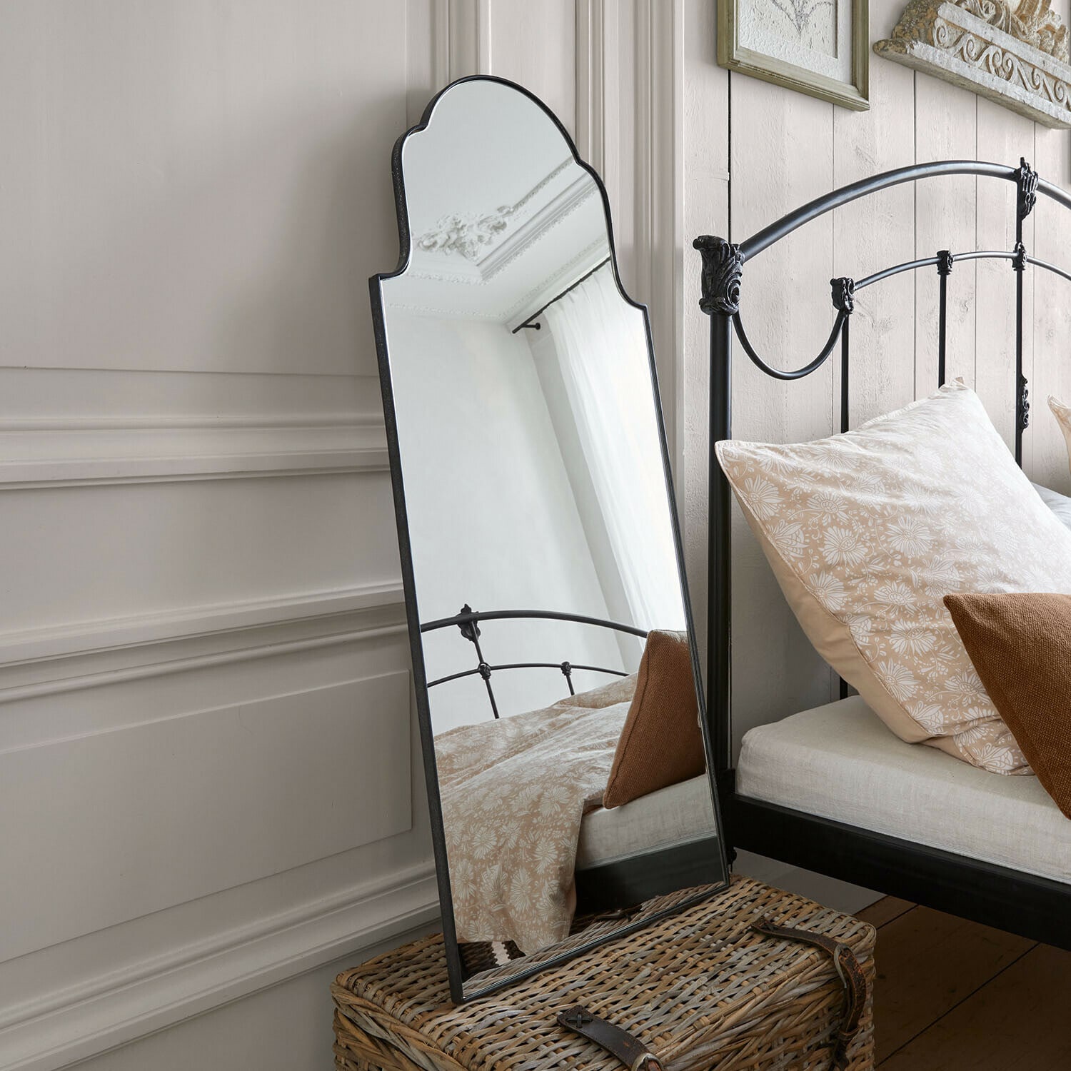 Miroir mural Tavreen Miroir sur pied avec cadre en métal noir décoratif dans une chambre avec lit et coussins beiges
