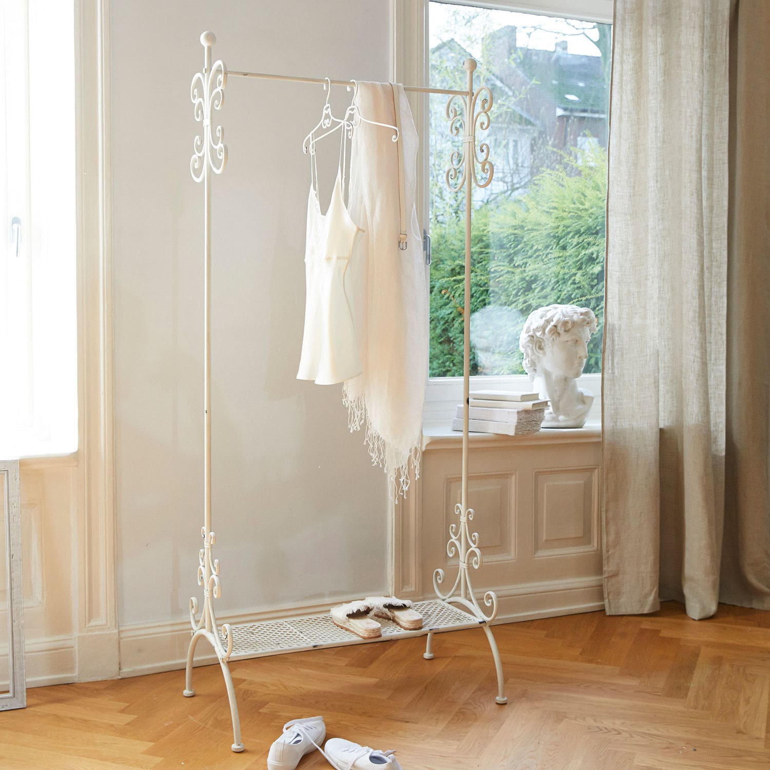 Portant Épinay Porte-vêtements en métal blanc avec détails décoratifs et étagère à chaussures dans une pièce lumineuse