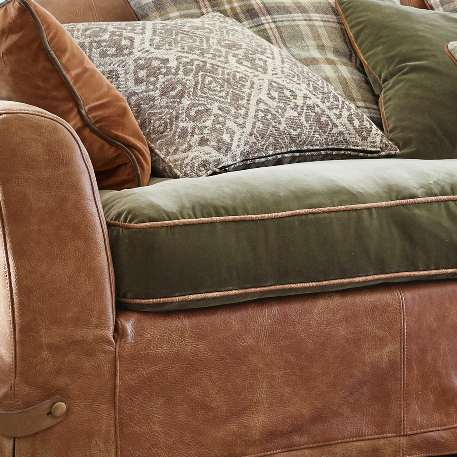 Bruine leren bank met groene fluwelen zitting en decoratieve kussens in rustieke stijl