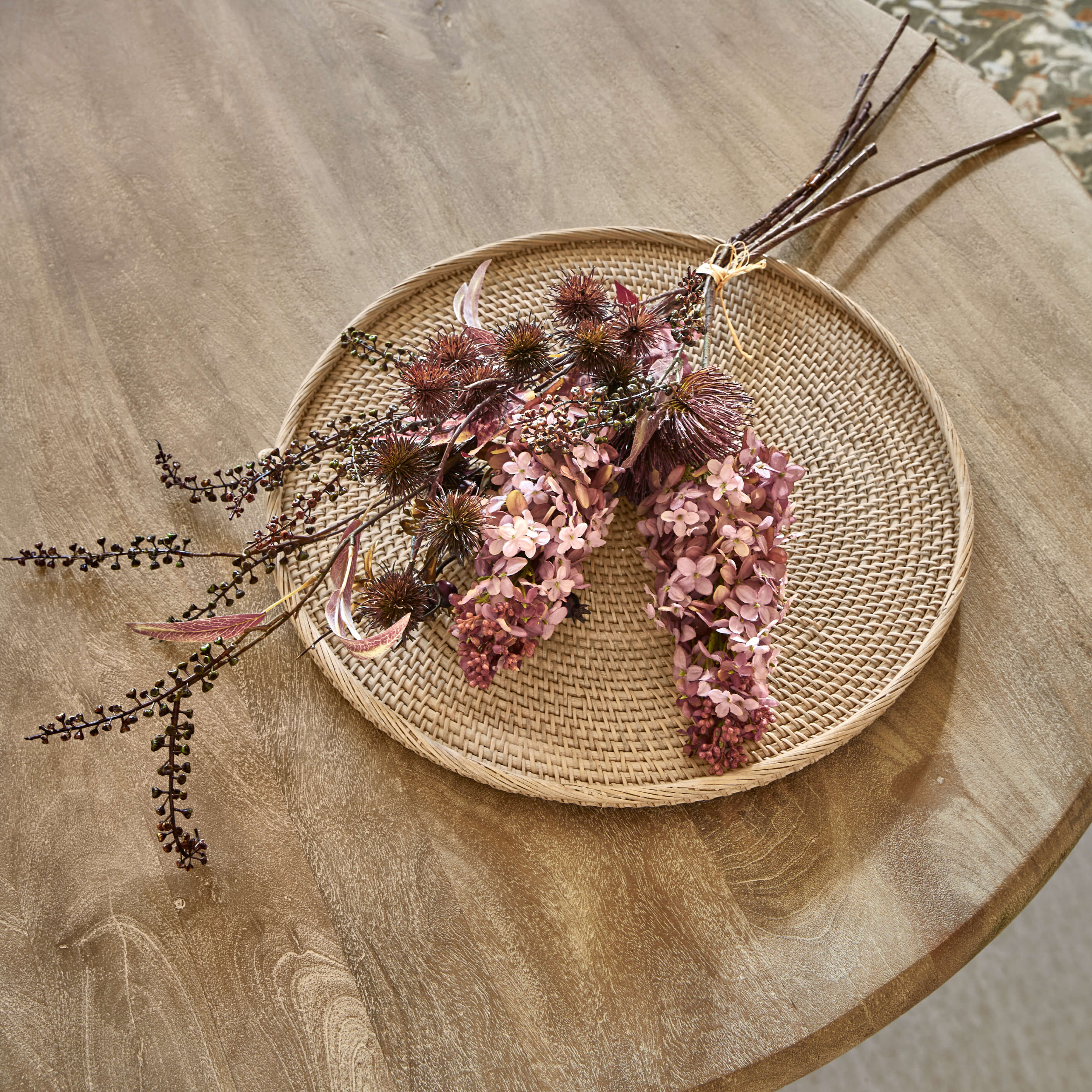 Decoratief boeket gedroogde bloemen in roze en bruine tinten op een gevlochten rotan schaal voor interieur