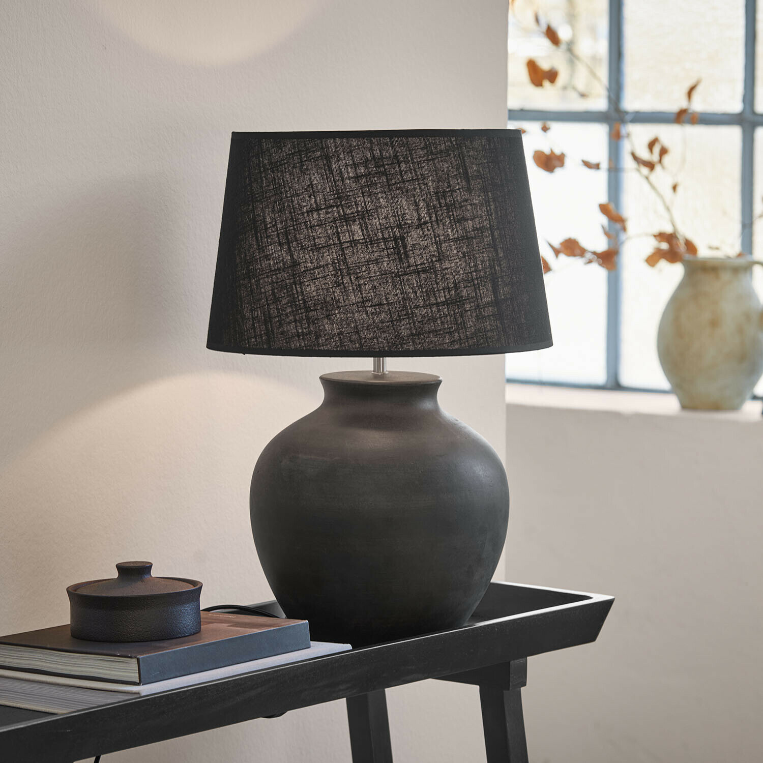 Tafellamp Branver Zwarte keramische tafellamp met stoffen kap op tafel met boeken en decoratie