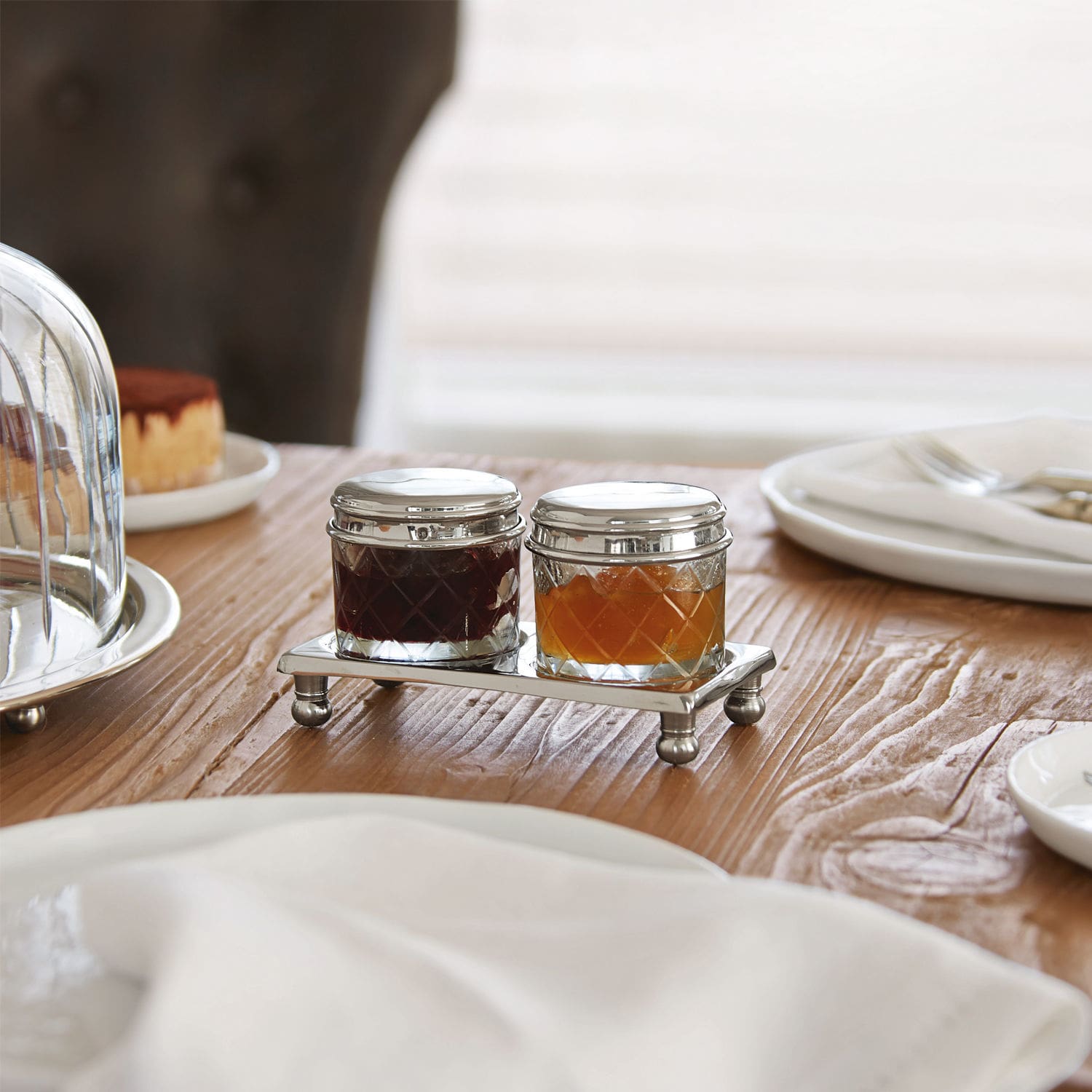 Potje set van 2 Aiton Glazen potjes met metalen deksels op zilveren standaard op houten tafel voor jamservering