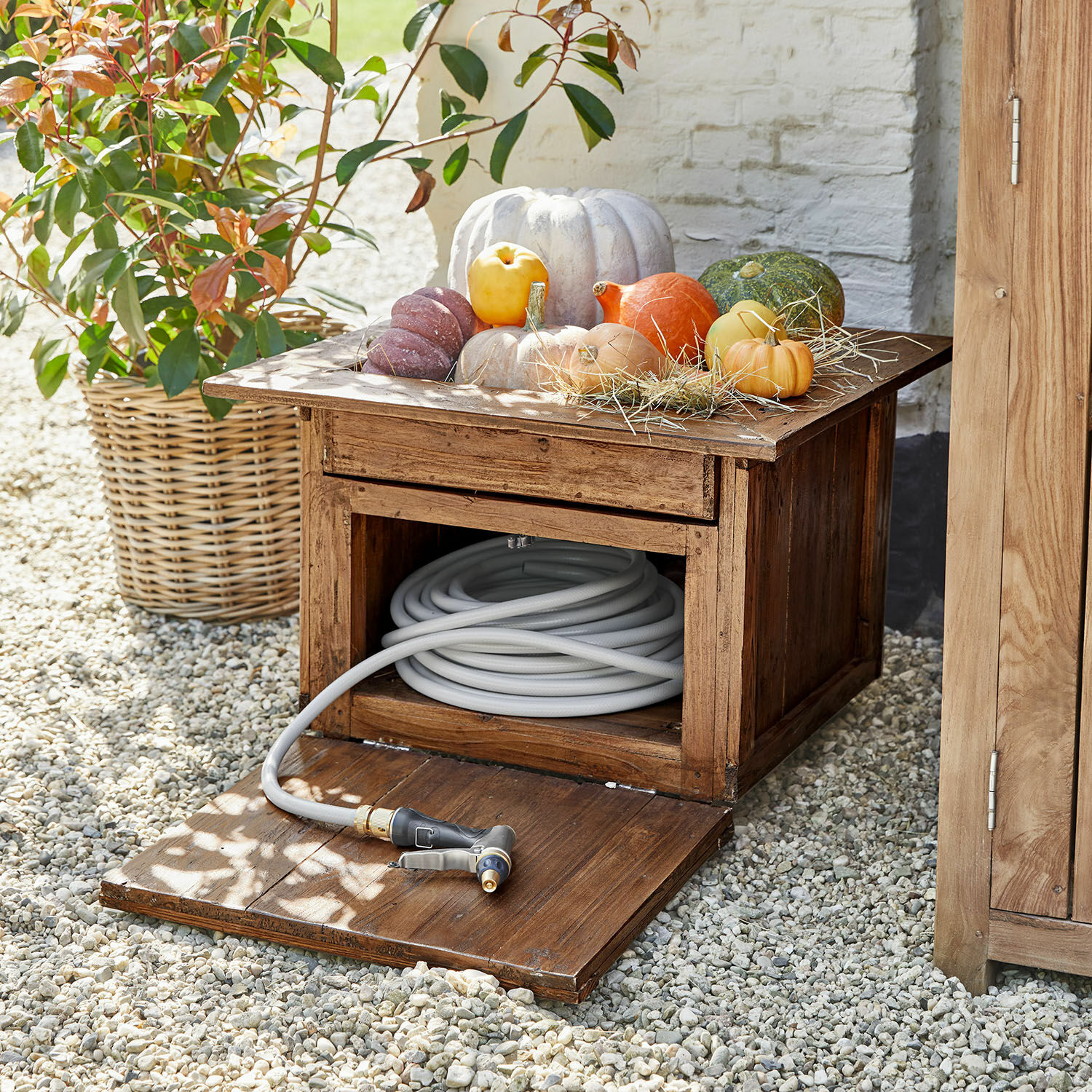 Tuinslangkast Fontabre Houten tuinkast met grijze tuinslang en decoratieve pompoenen bovenop
