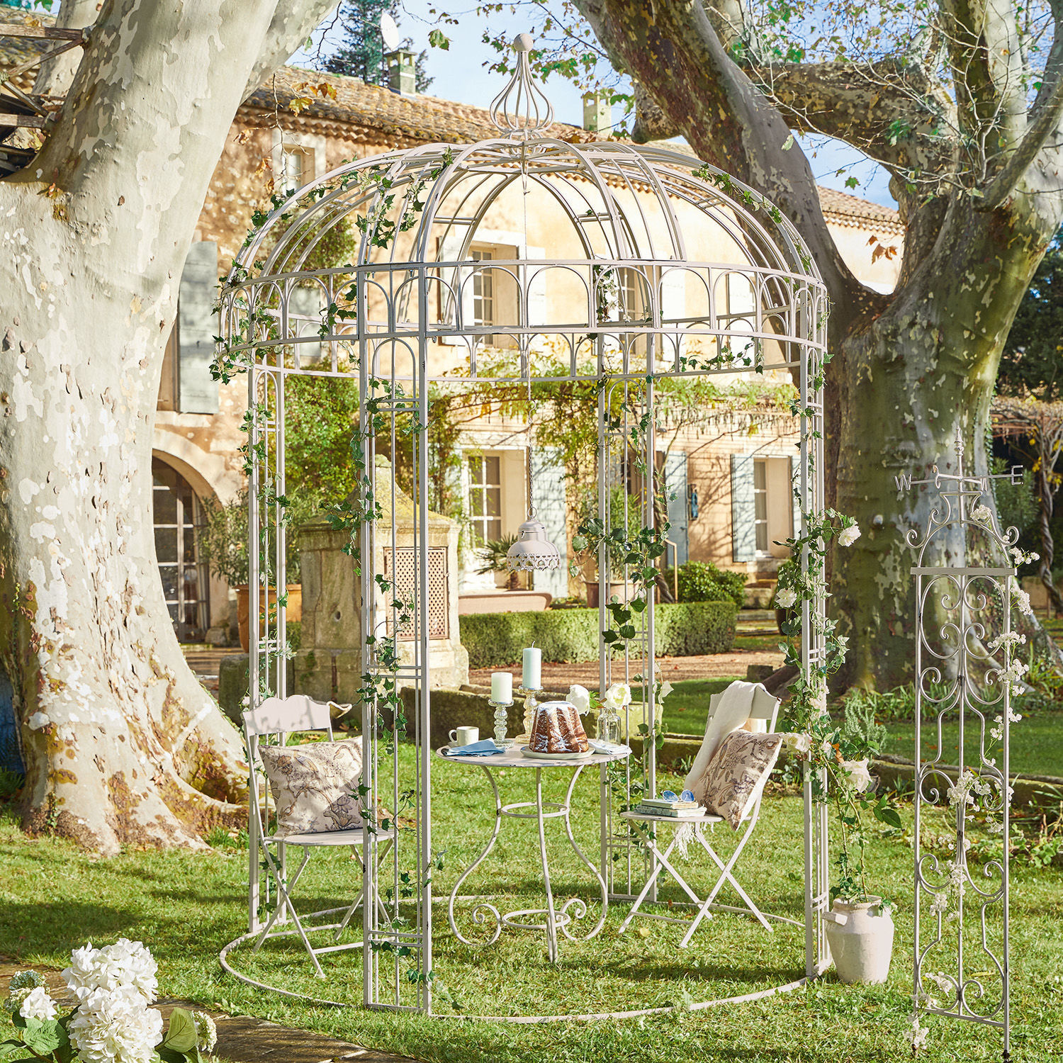 Gloriette Iolanda Kiosque de jardin en métal blanc avec chaises et table sur pelouse, décoré de lierre vert