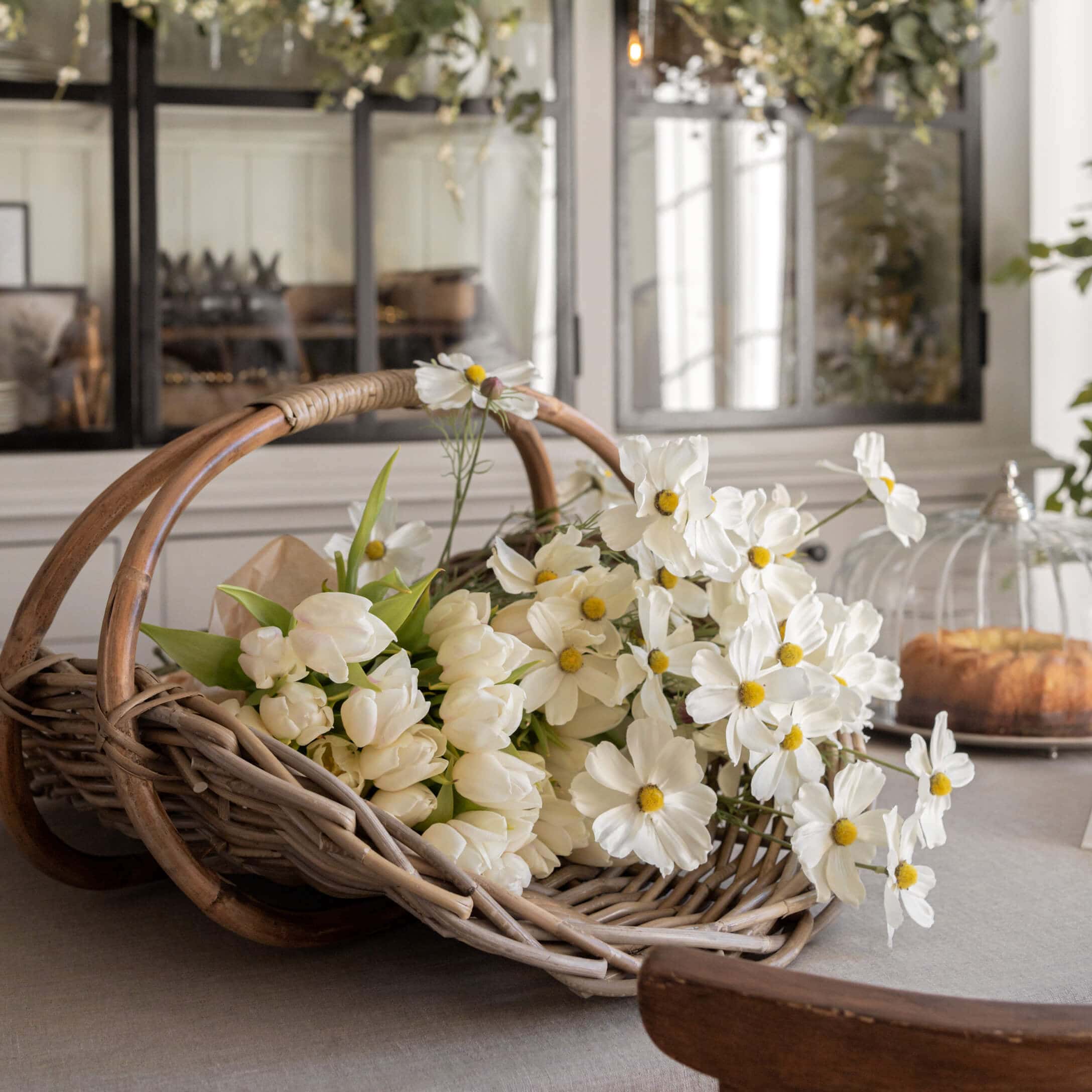 Panier en osier avec tulipes blanches et fleurs décoratives sur une table dans un intérieur lumineux