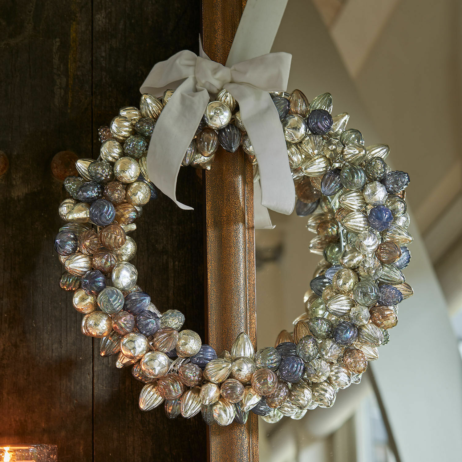 Krans Azélisse Decoratieve krans van gekleurde glazen bollen met witte strik aan houten deur