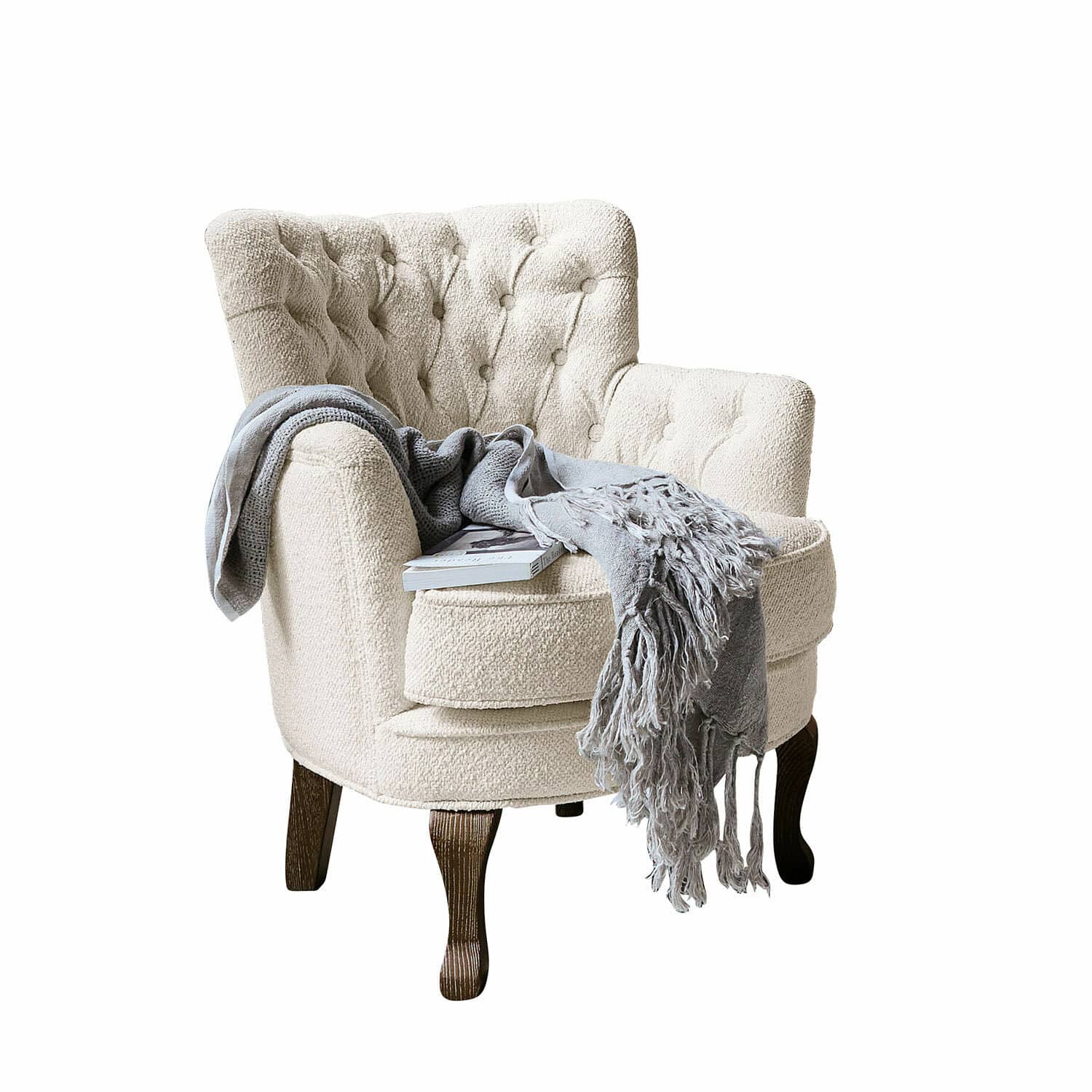 Fauteuil Calgary Beige bouclé fauteuil met donkere houten poten, grijze deken en boek erop