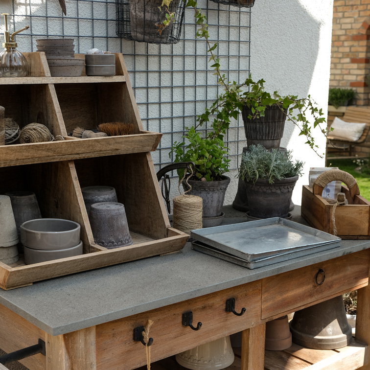 Houten tuintafel met betonnen blad, plantenpotten, tuingereedschap en touwen