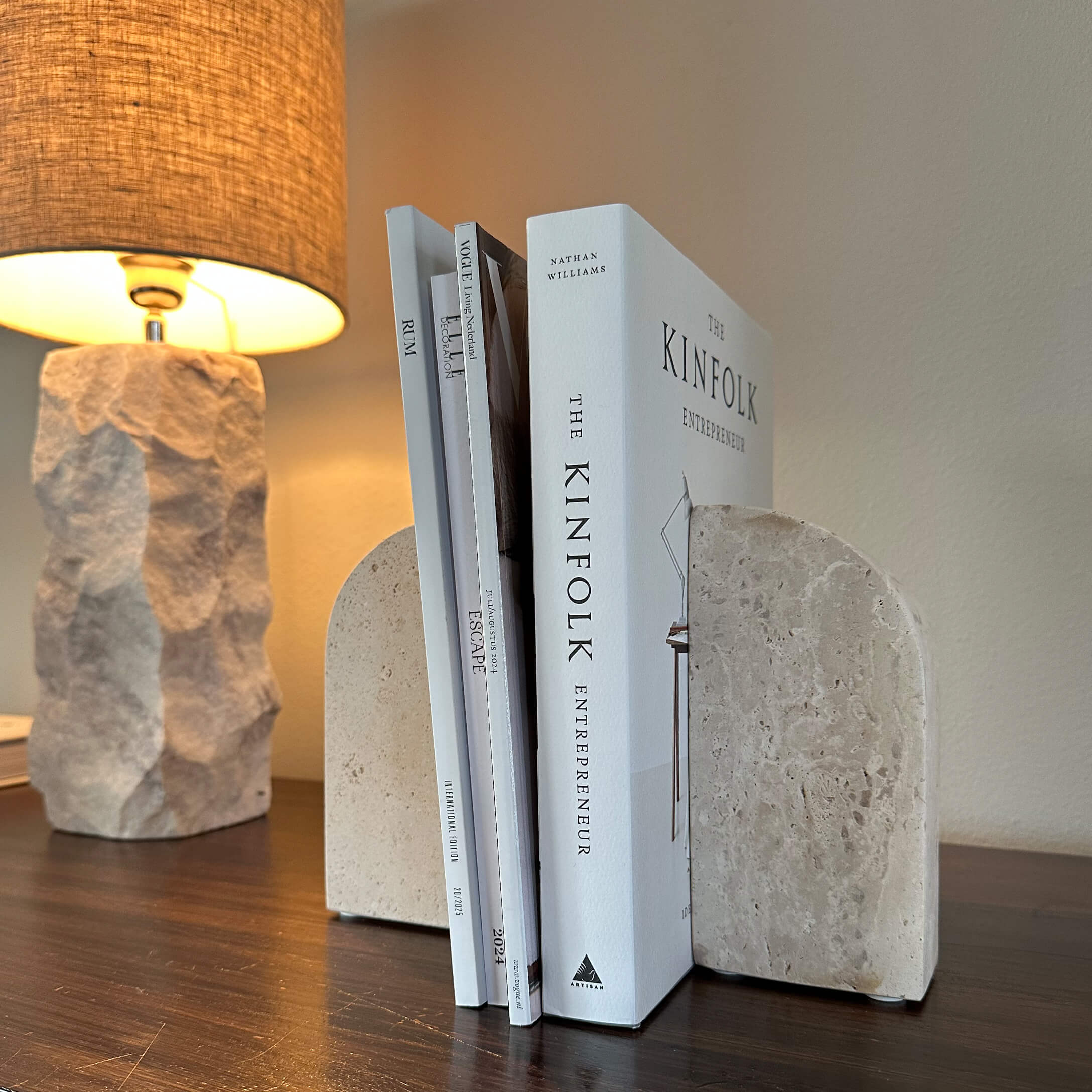 Serre-livres en pierre beige sur une table en bois avec une lampe allumée en arrière-plan