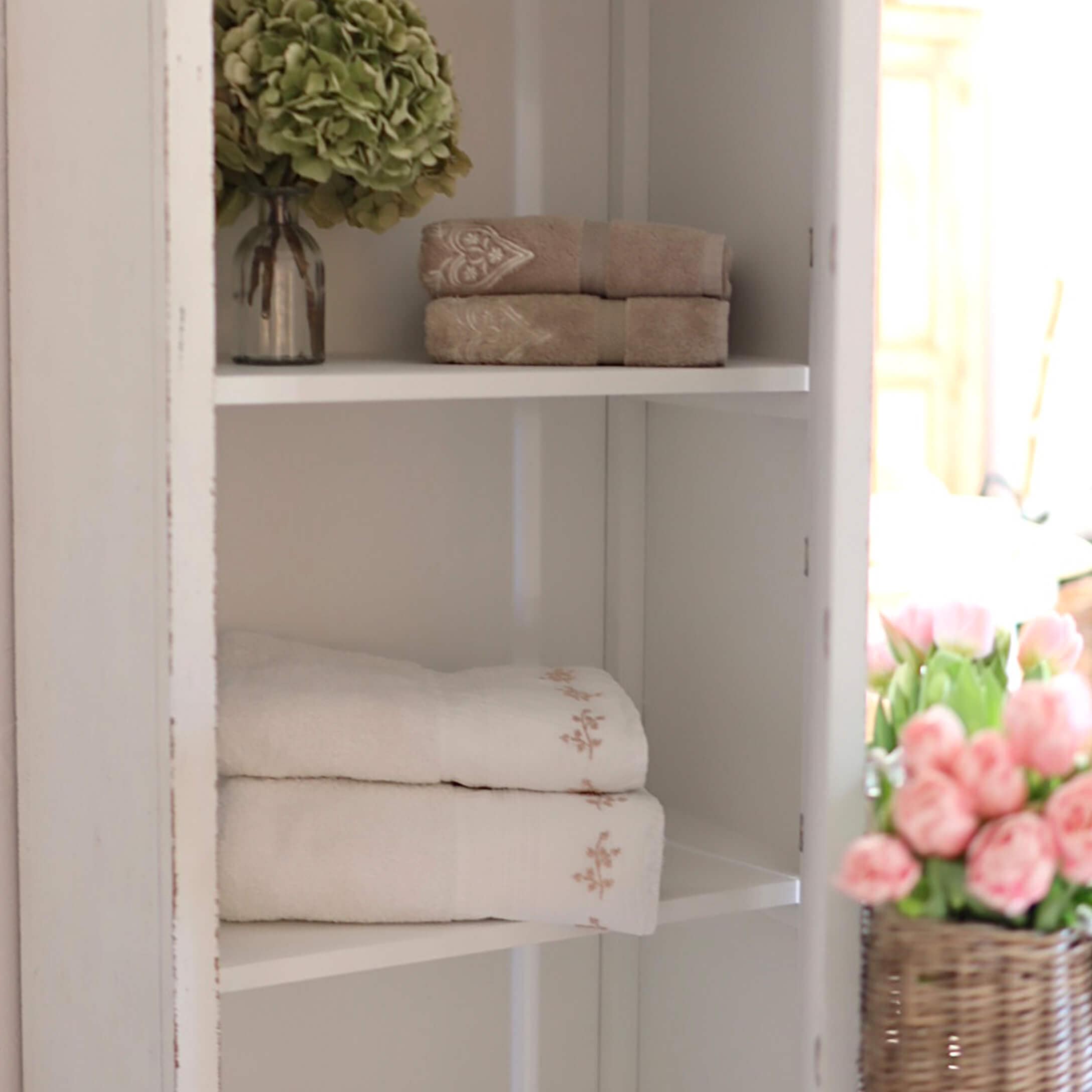 Serviettes en coton beige et blanc avec broderie délicate sur une étagère blanche