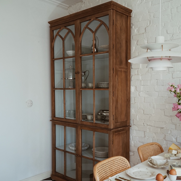Houten vitrinekast met glazen deuren in vintage stijl in eetkamer met witte bakstenen muur